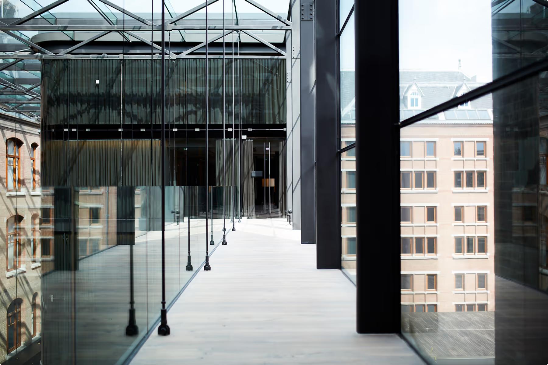 Modern rooftop terrace with floor-to-ceiling glass panels, dark columns, and city views