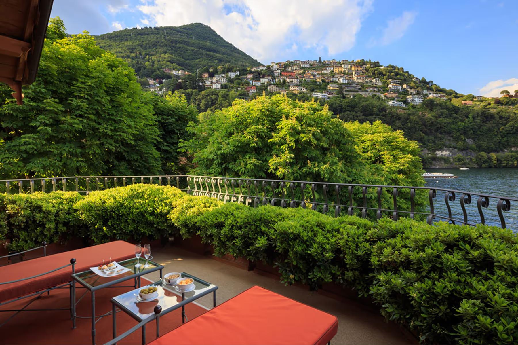 Villa d’Este: covered terrace with cream lounge seating overlooking the lake from a hillside vantage