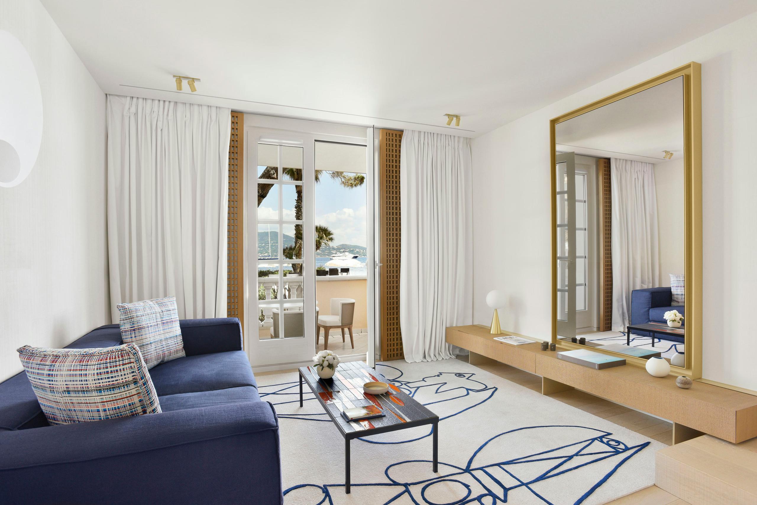 Cheval Blanc St-Tropez: light-filled suite with navy sofa, mirror, and terrace access