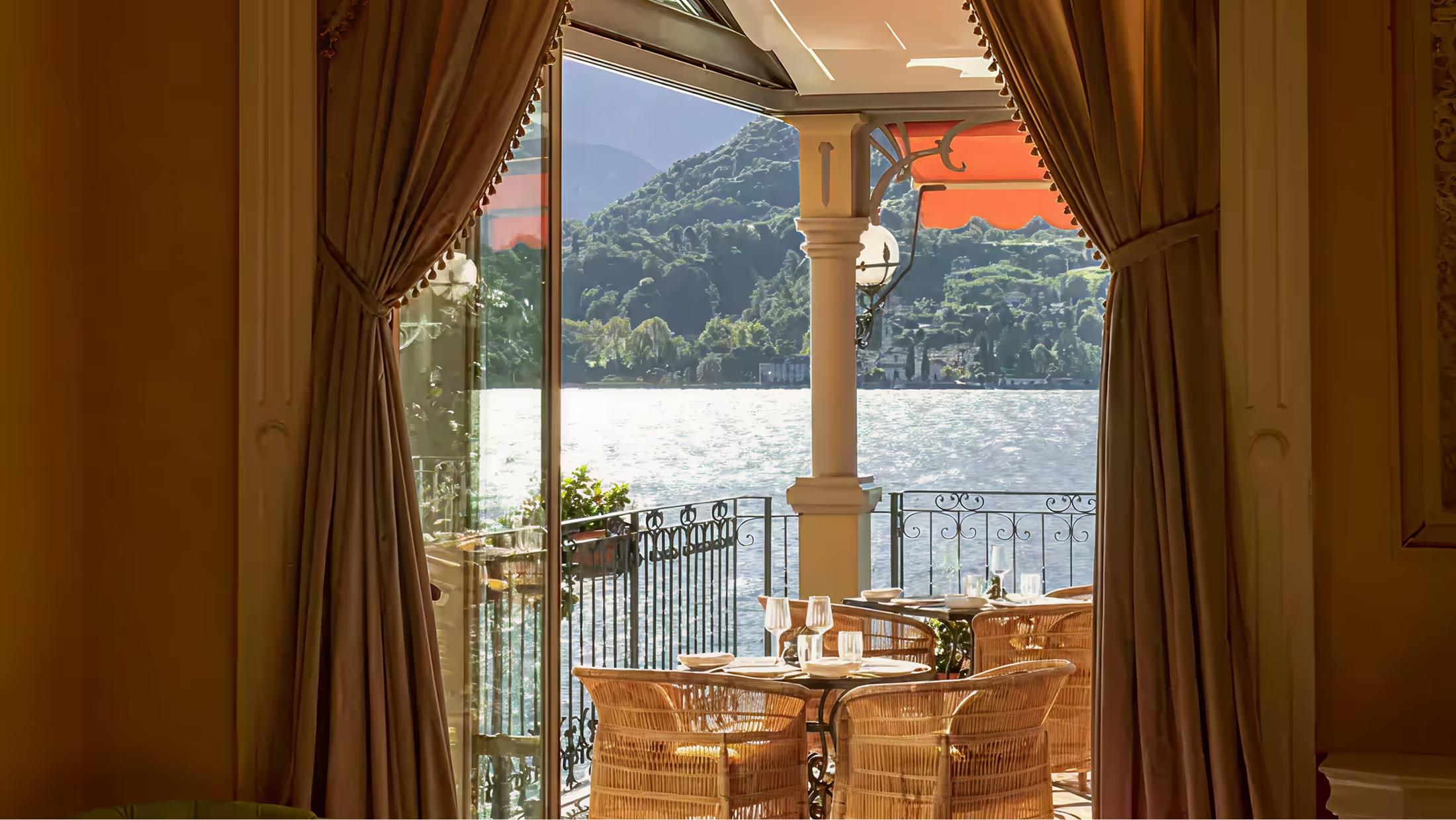 View from a suite terrace toward Lake Como framed by gold curtains and wood doors