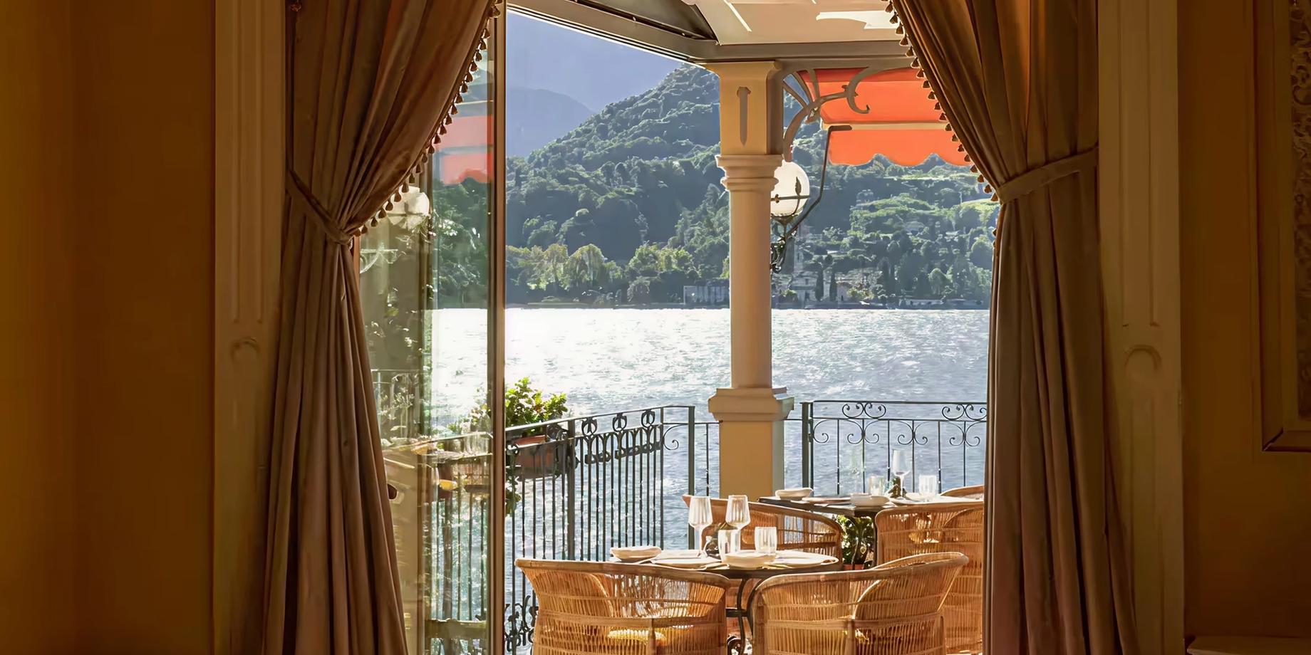 View from a suite terrace toward Lake Como framed by gold curtains and wood doors