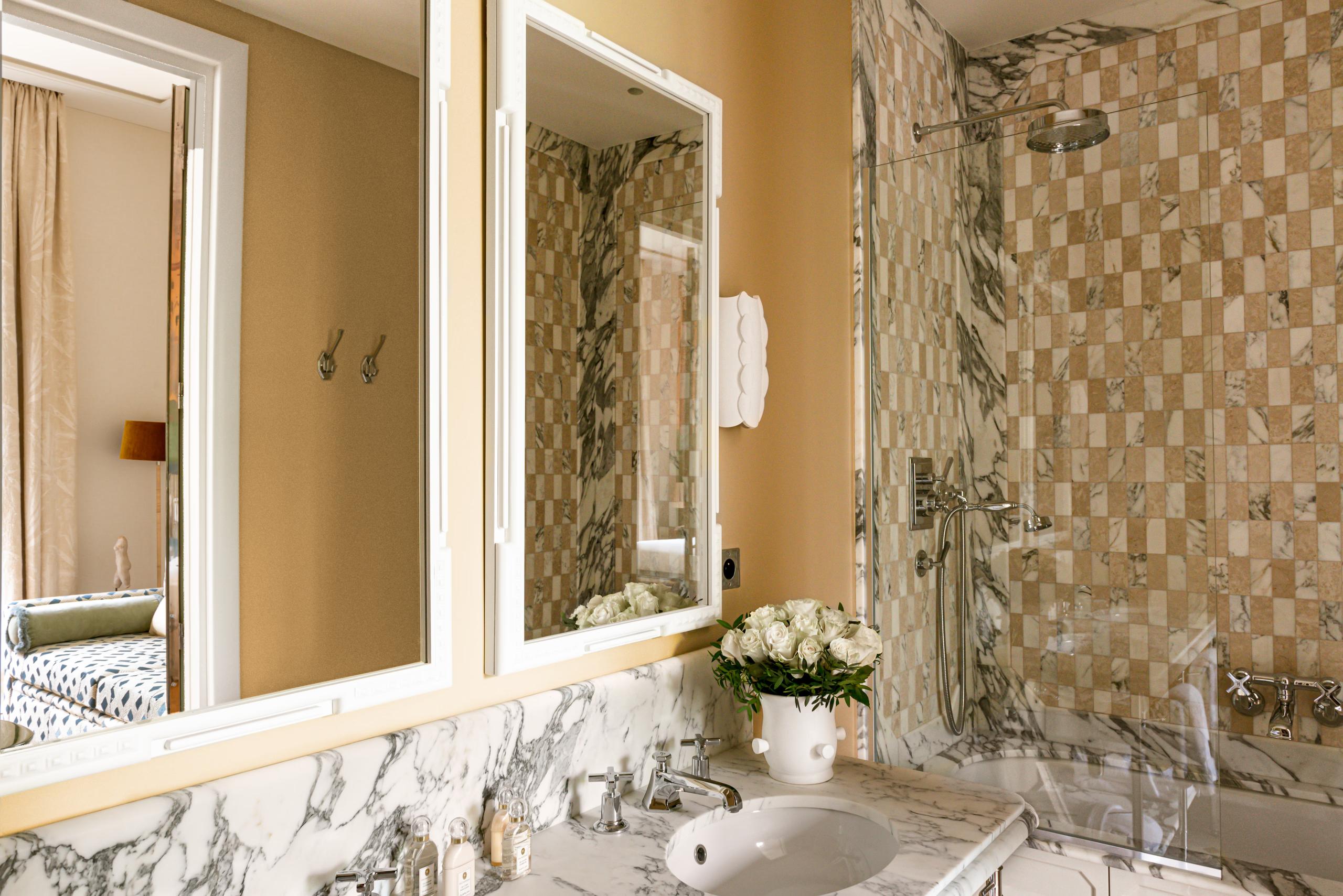 Saint James: bathroom with marble sink, patterned tile detail, and wood cabinetry