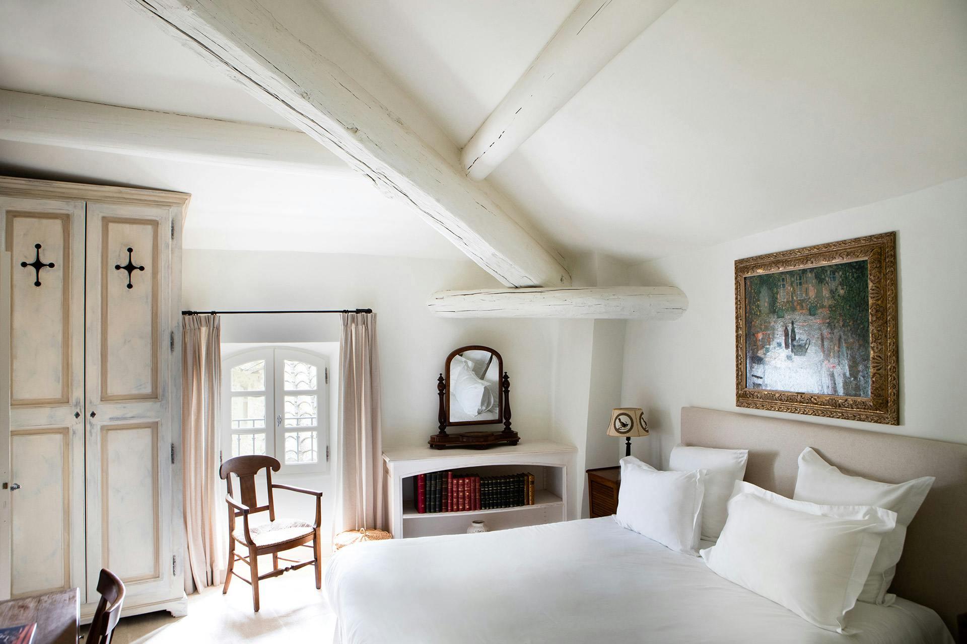 Bedroom under sloped ceiling with exposed beams and fireplace