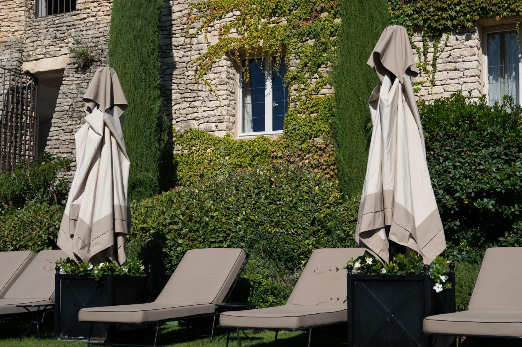 Stone terrace with closed umbrellas and lounge chairs beside stone walls