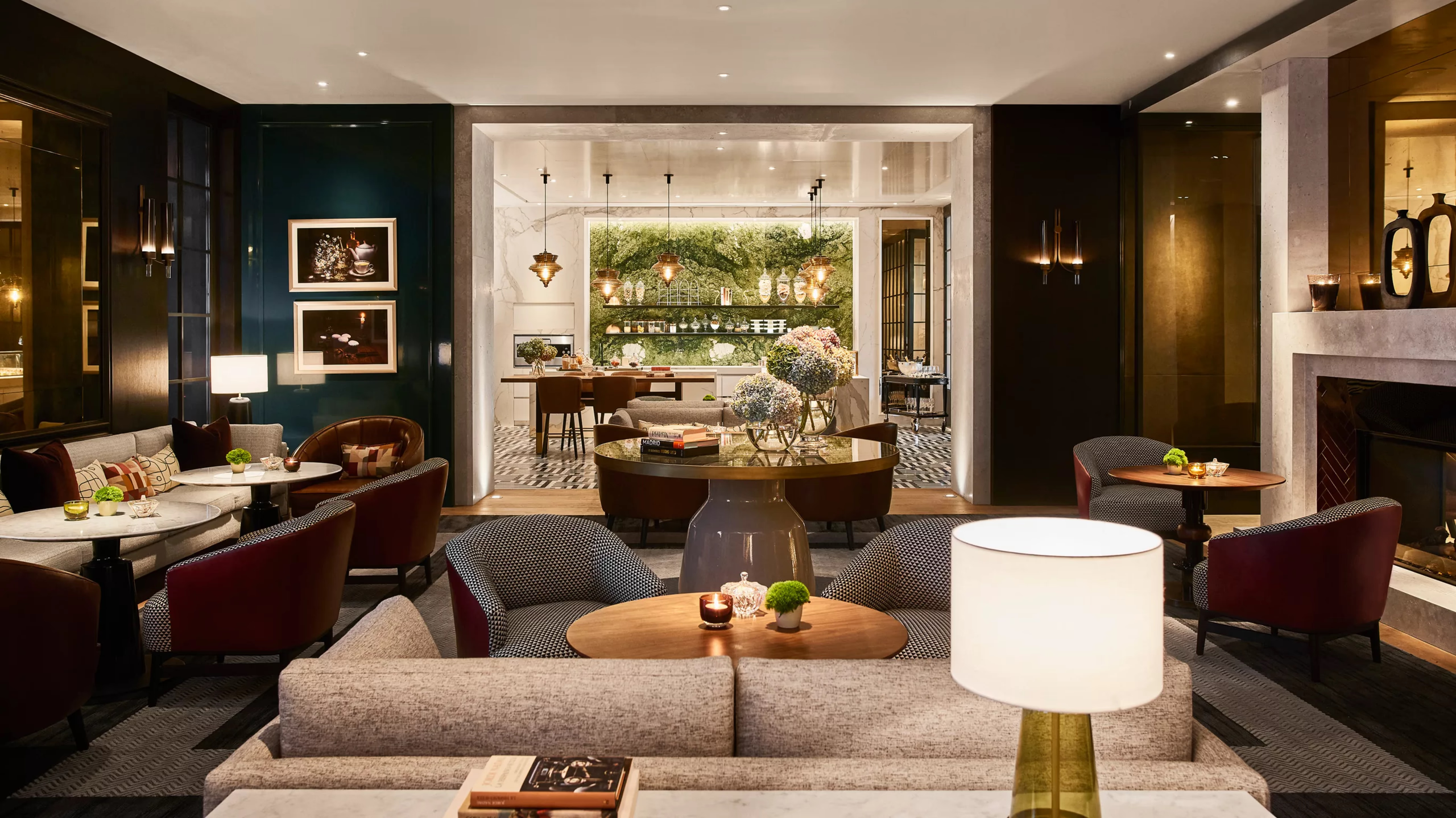 A lounge area with dark walls, fireplace, multiple seating zones, and warm wood paneling