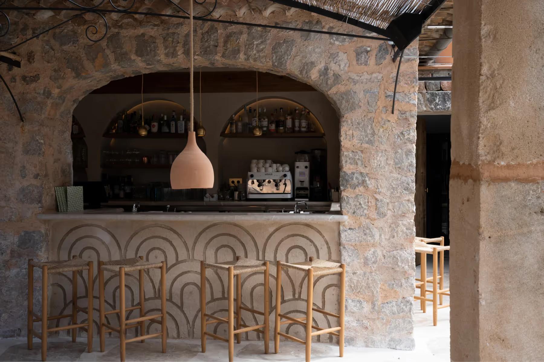 Bar counter with terracotta tile work, bottle shelving, and hanging pendant light fixture