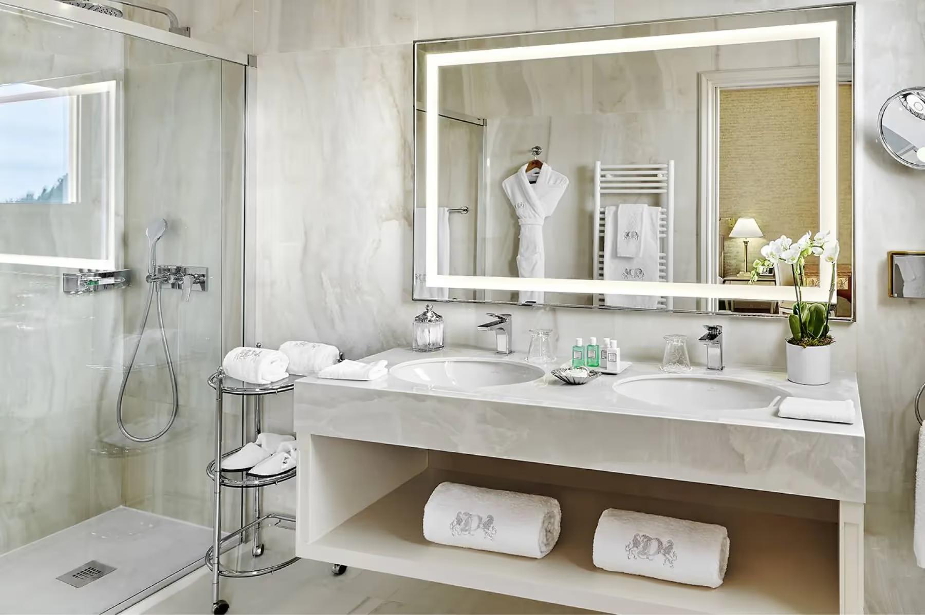 Modern white bathroom with double vanity and glass-enclosed shower
