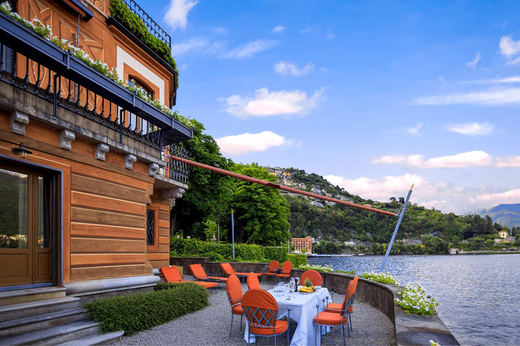 Villa d’Este: terrace with coral lounge chairs on a wooden boathouse overlooking the lake at sunset