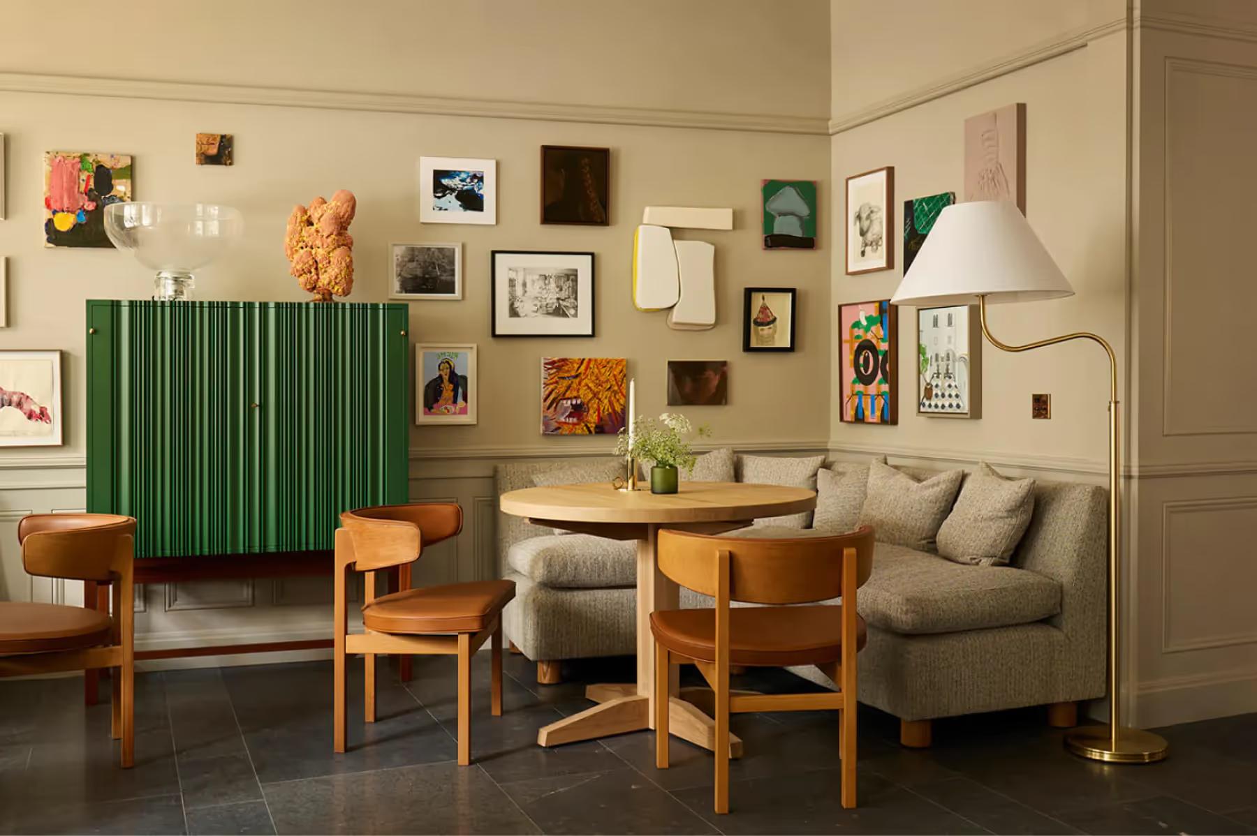 Ett Hem: a lounge with green accent wall, wooden furniture, and wall-mounted artwork collection
