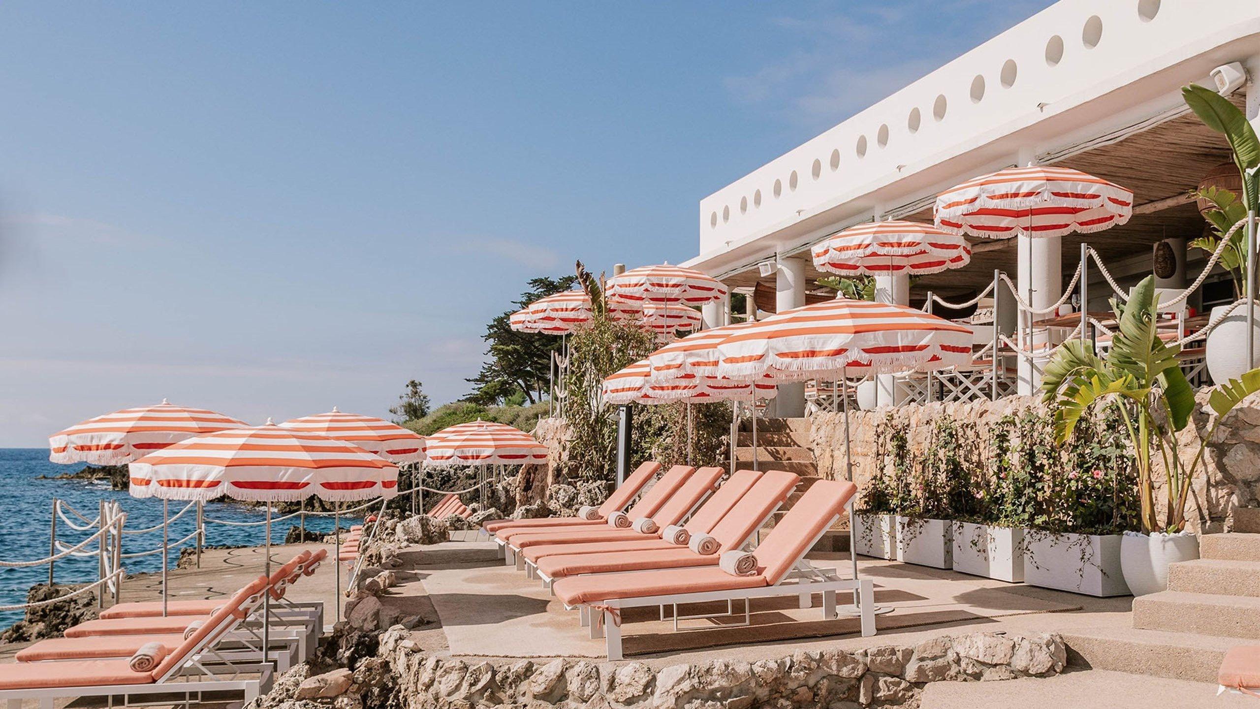 Maybourne Riviera: waterfront terraces with orange umbrellas and lounge seating