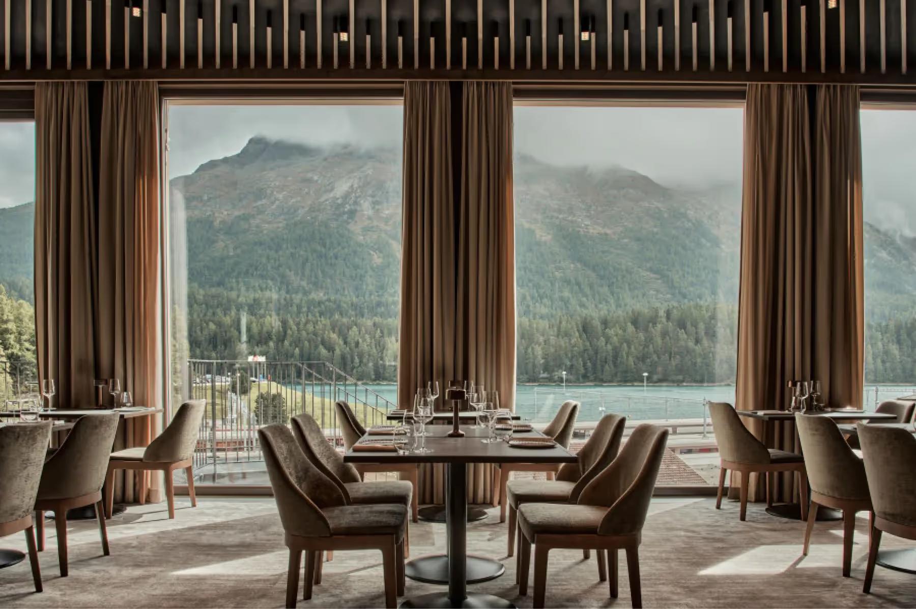 Grace La Margna St. Moritz: restaurant with wood paneling, large windows framing alpine landscape, round dining tables