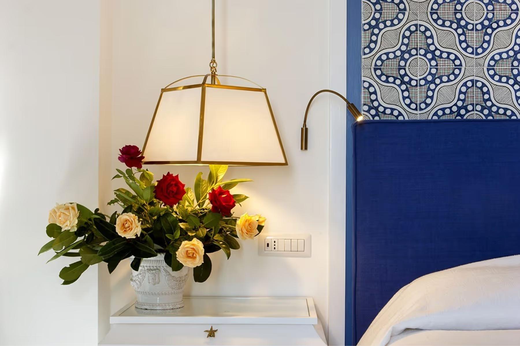 Il San Pietro di Positano: bedside table with golden hanging pendant lamp above fresh flower arrangement in vase