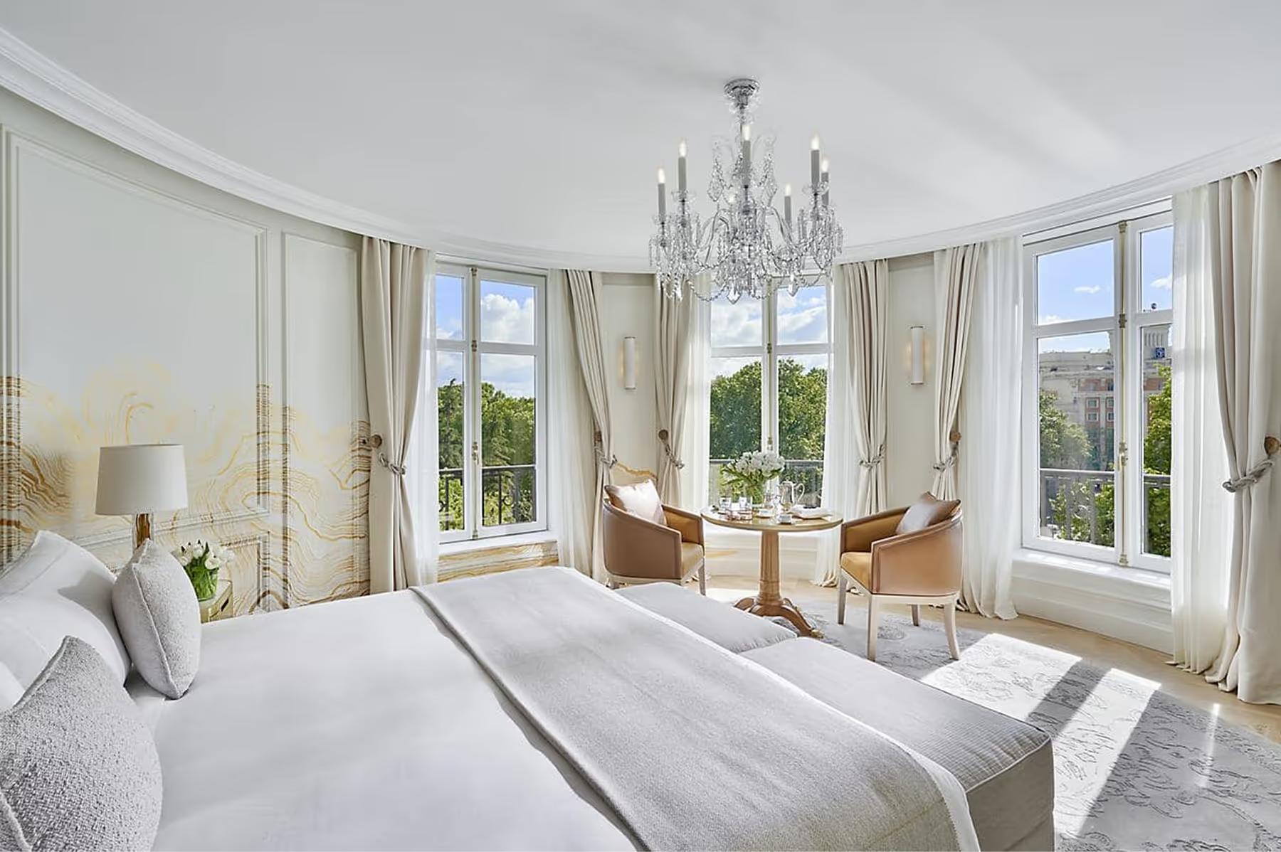 Bedroom with white bedding, tall windows, and brass table lamps
