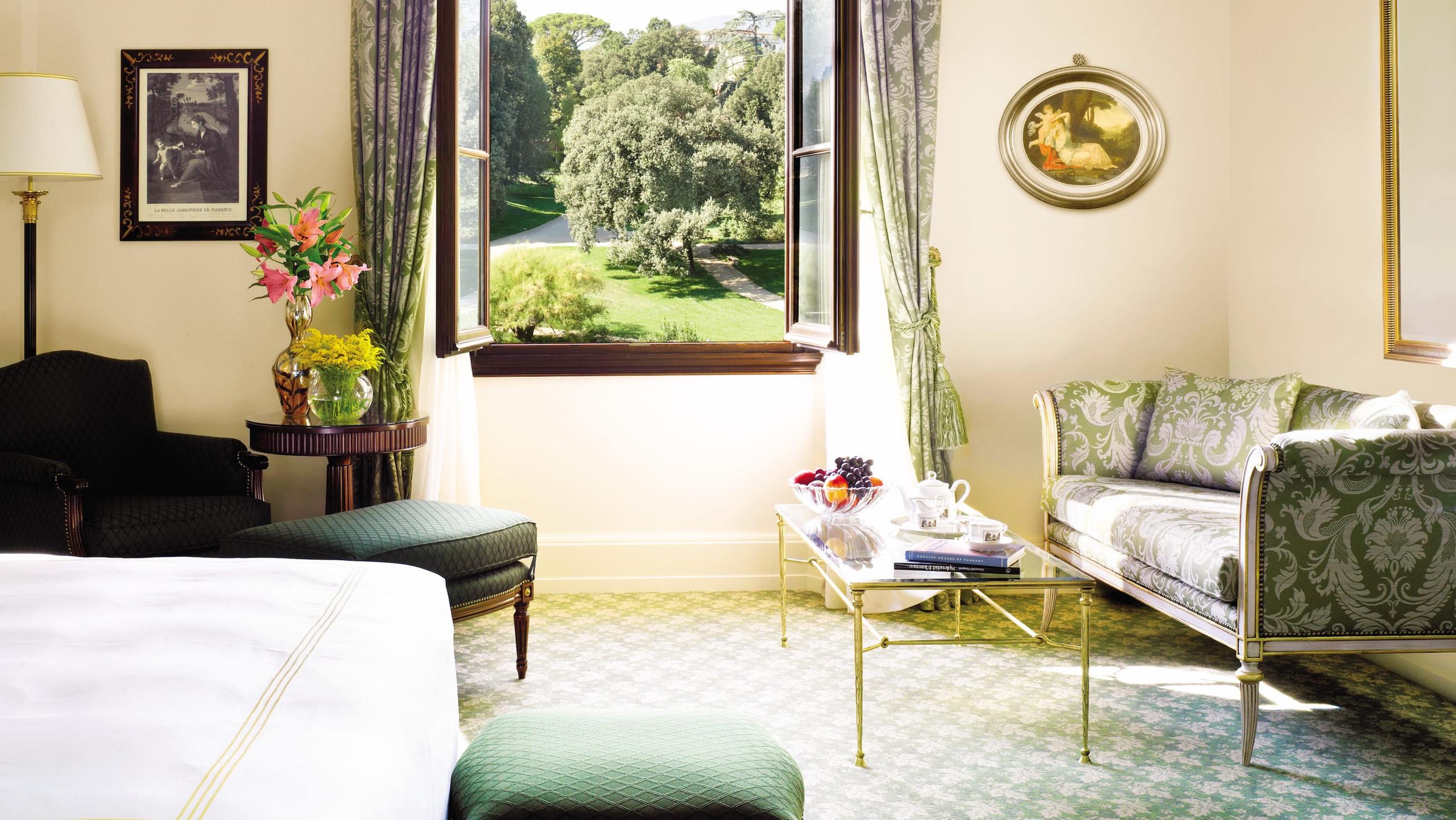 Four Seasons Hotel Firenze: bedroom with pale walls, garden views through tall windows, and pale green upholstered seating
