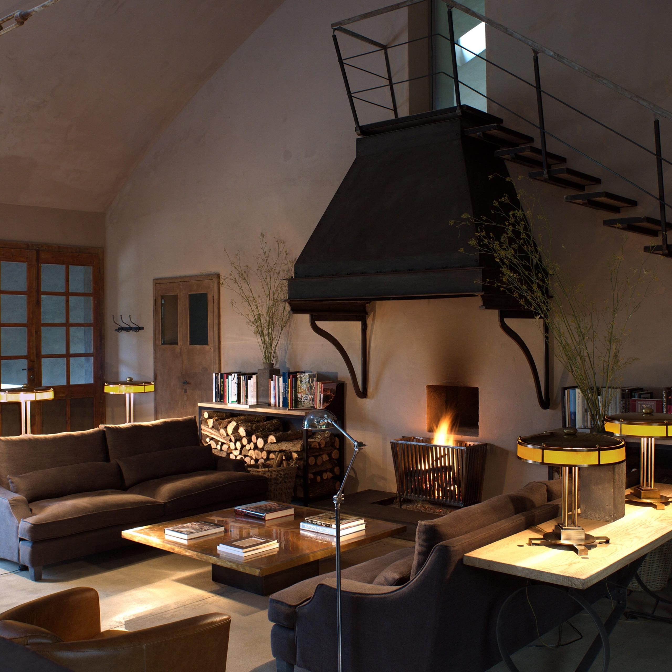 Castello di Reschio: a double height living room with a black hooded fireplace, leather sofas, and a mezzanine loft above