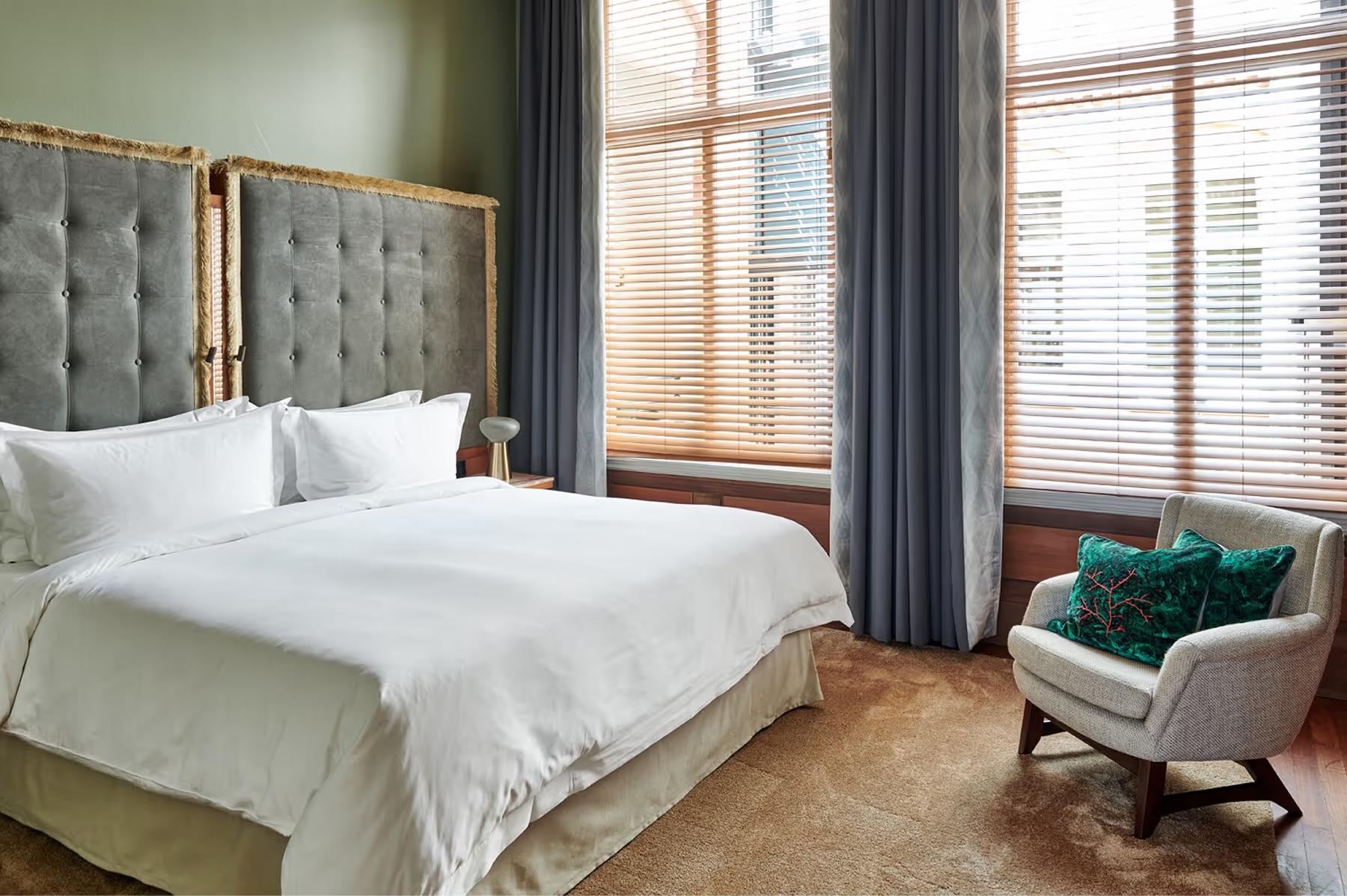 De L’Europe Amsterdam: bedroom with sage green walls, light upholstered seating, and tall windows with river views