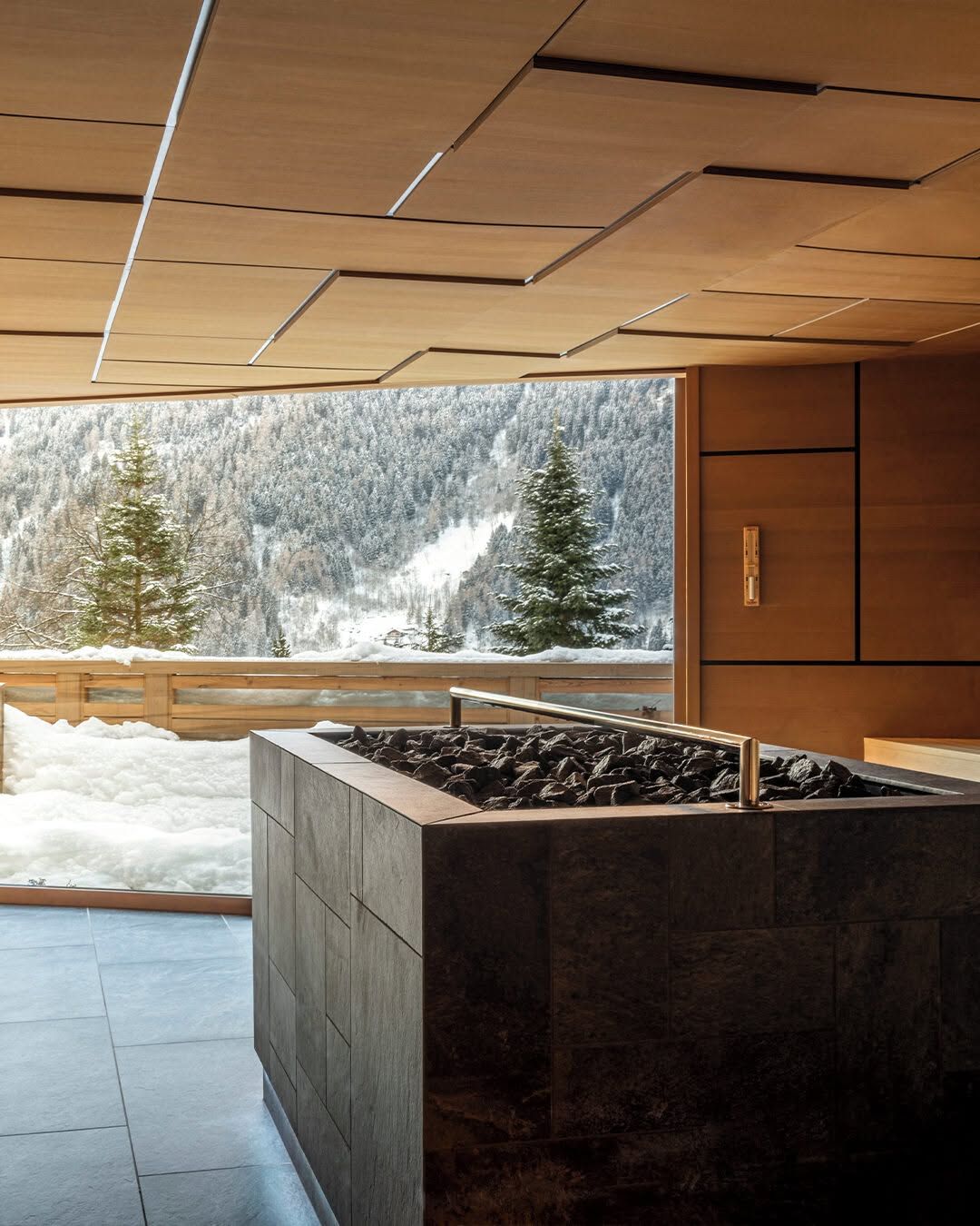 A sauna at Lefay Dolomiti with a panoramic window onto a snow-covered forest slope