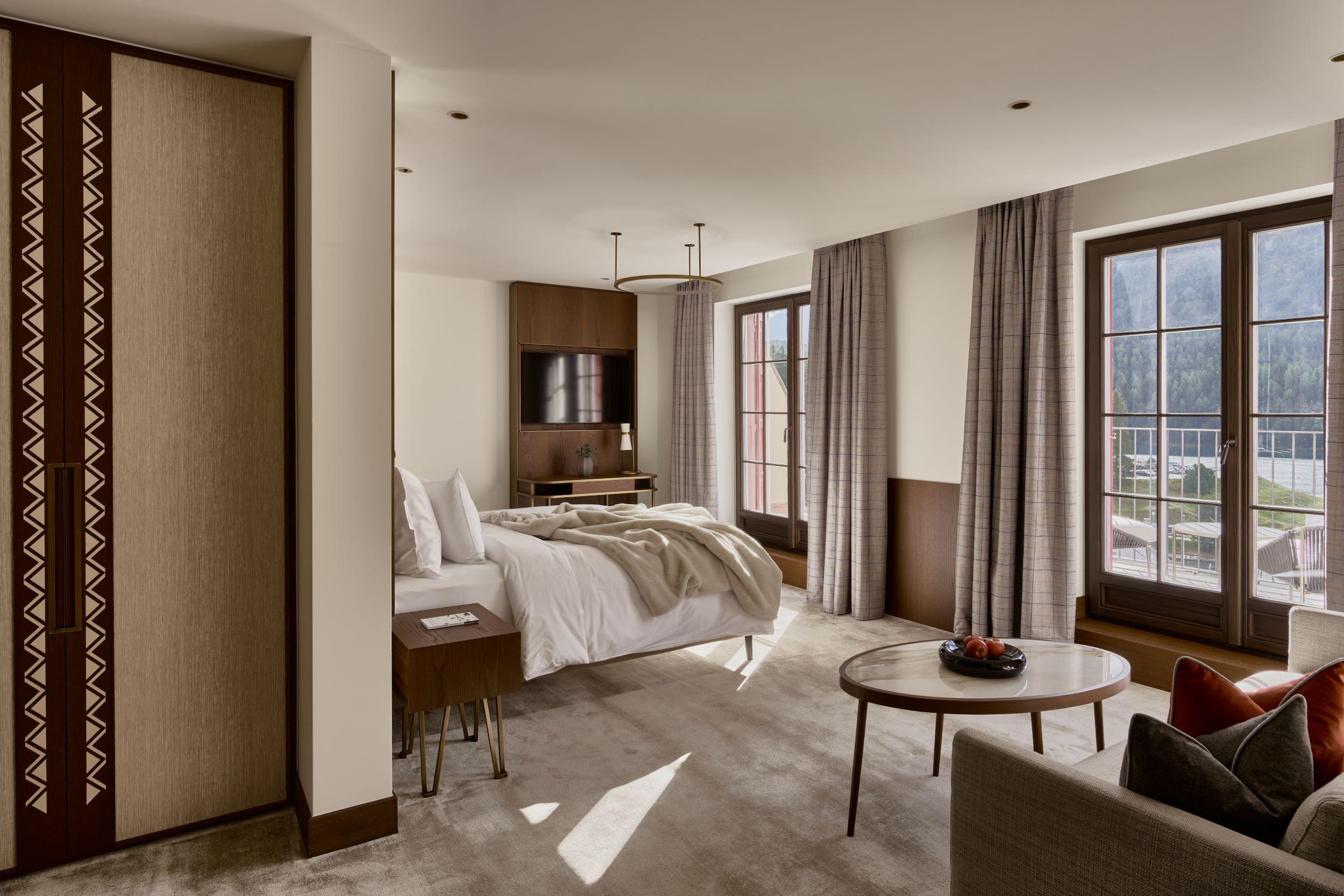 Grace La Margna St. Moritz: bright bedroom with white bedding, wooden built-ins, and glass doors to mountain-view terrace