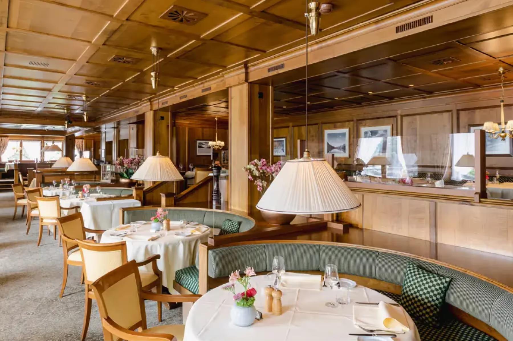 Suvretta House: a restaurant with wood walls, table lamps, white-clothed settings, and warm ambient lighting