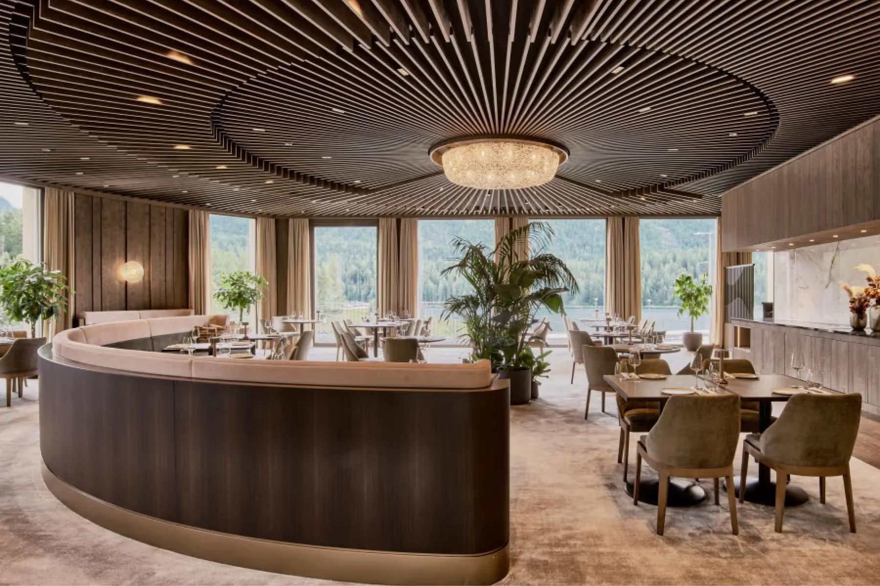 Modern dining space with curved dark wood bar, pendant lighting, and floor-to-ceiling windows