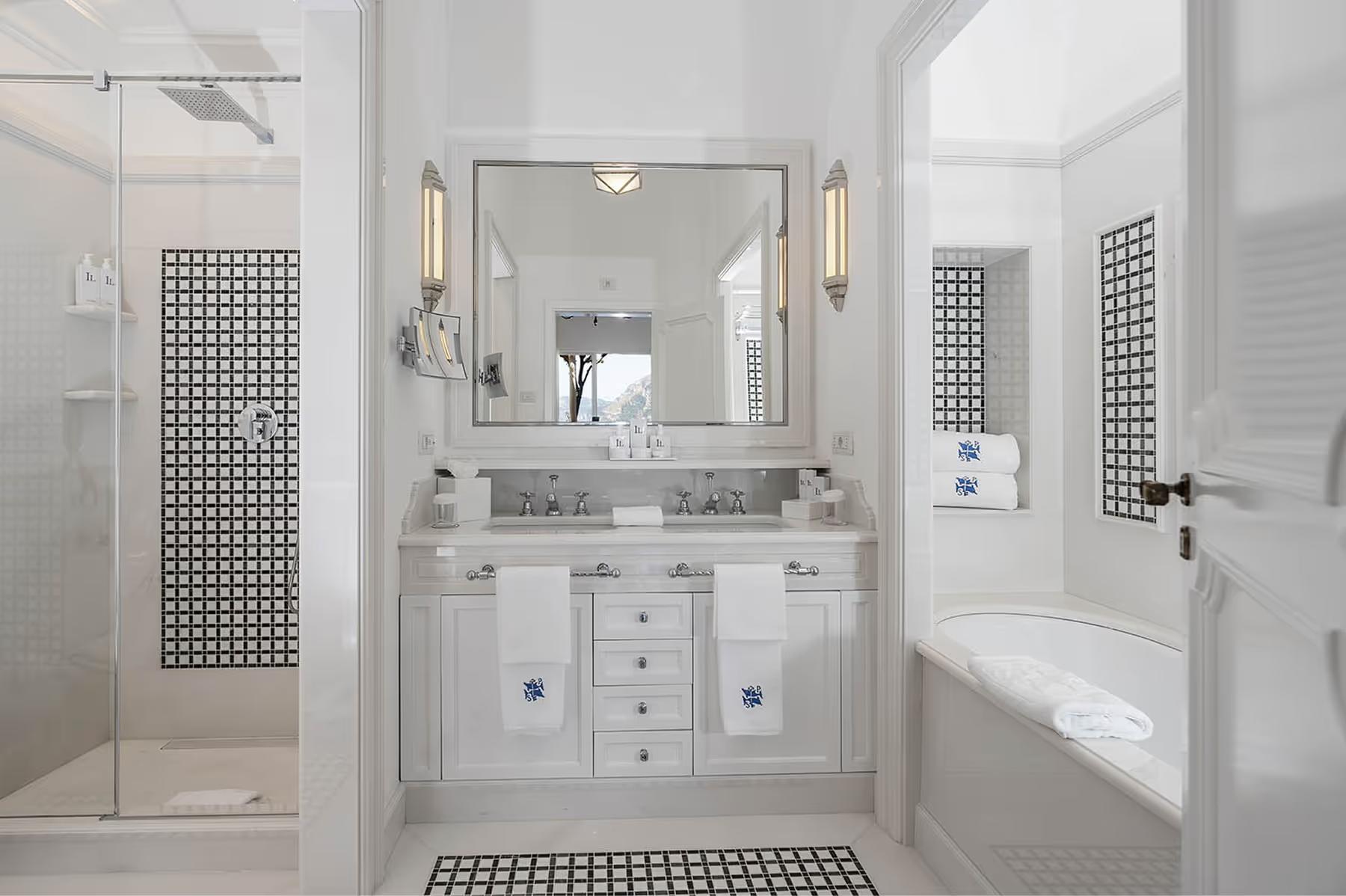 Neutral-toned bathroom with marble vanity, large mirror, brass sconces, and spa-like finishes