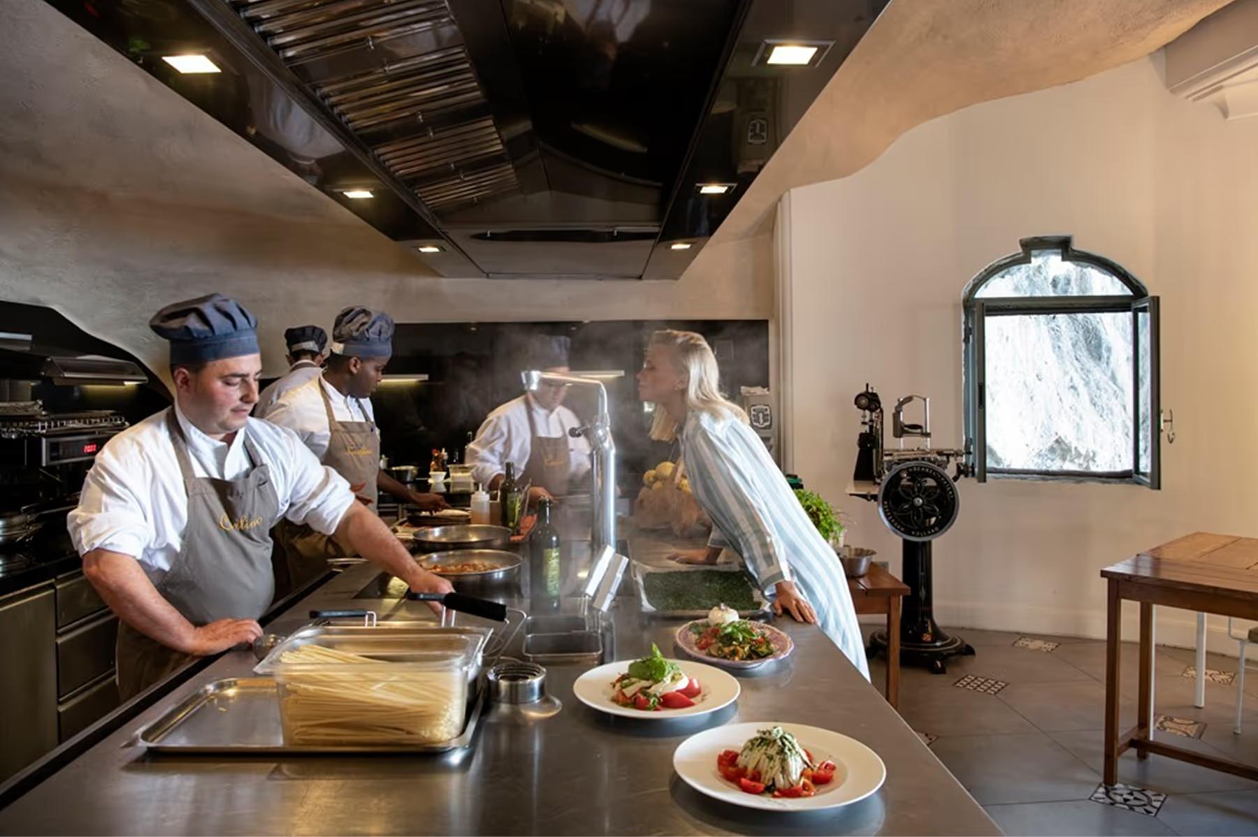 Open kitchen with chefs in white, plated dishes on counter, and warm interior lighting