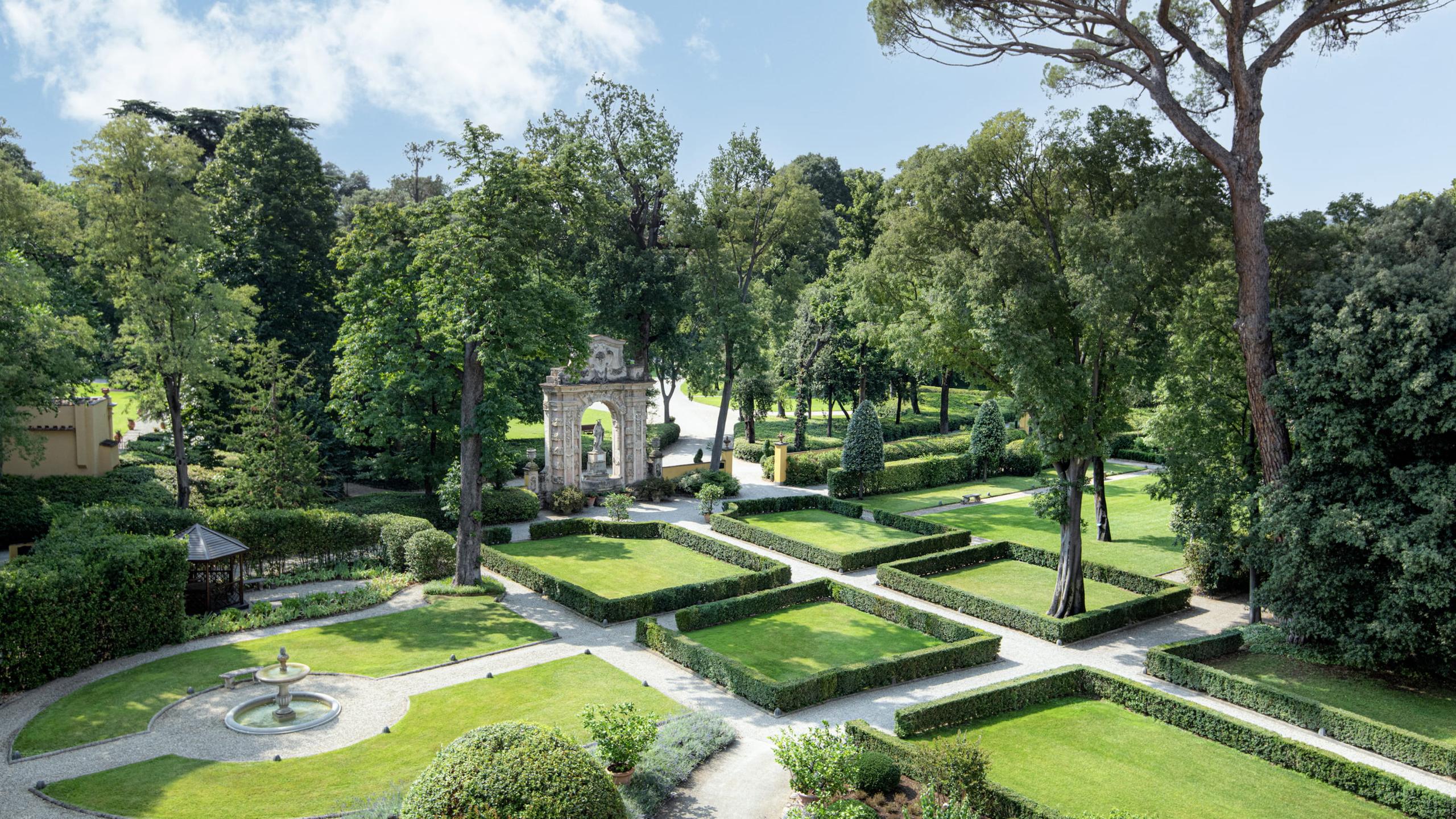 Four Seasons Hotel Firenze: manicured Renaissance gardens with geometric hedgerow paths, fountains, and mature shade trees