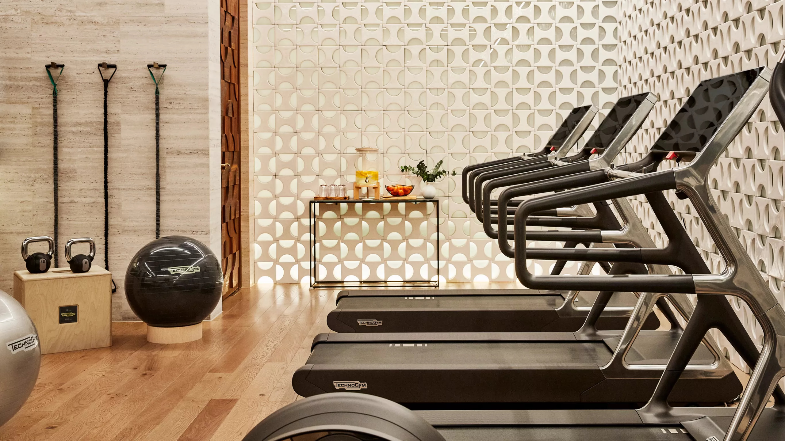 A fitness center with treadmills, geometric tile flooring, and minimalist design