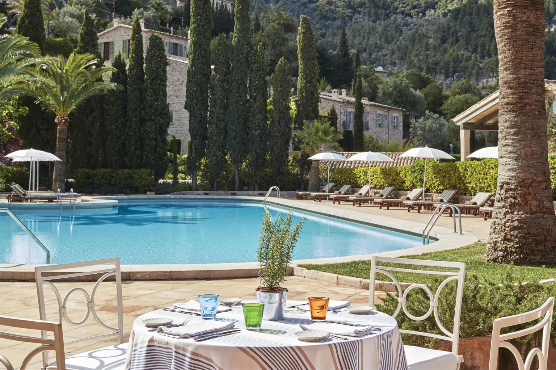 Poolside dining table with Mediterranean valley and building views in afternoon light