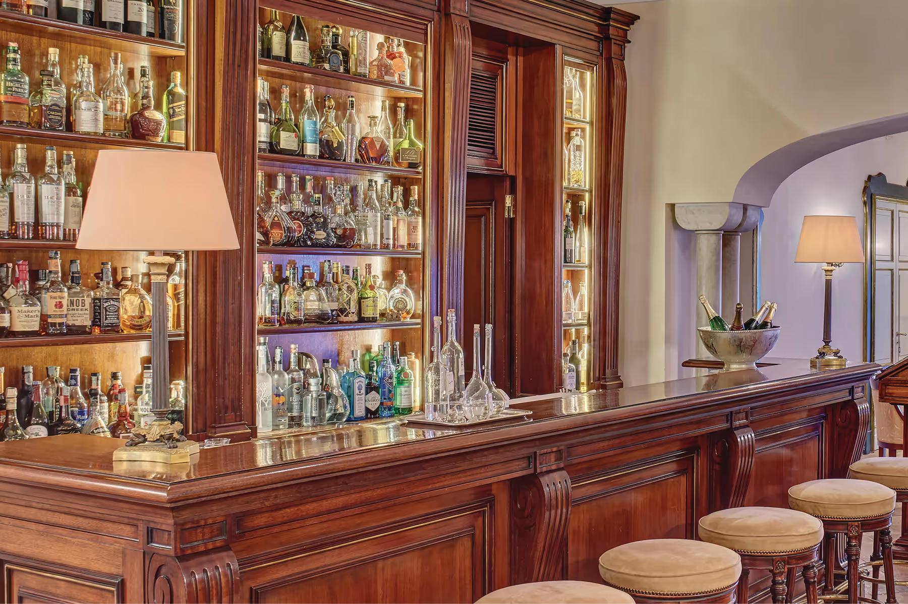 Mahogany bar counter with illuminated shelving displaying spirits and cocktail service area