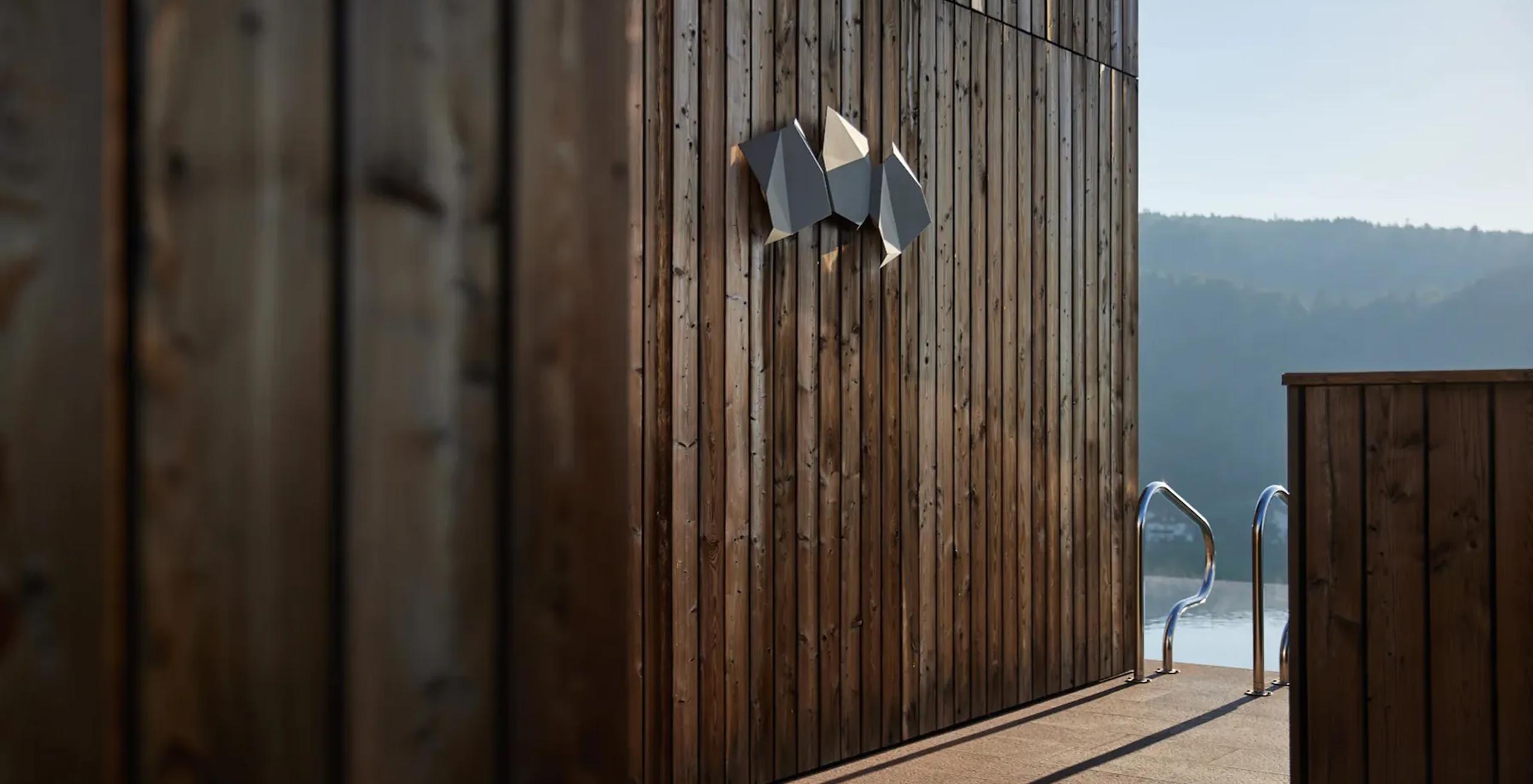 Wooden exterior deck and slatted wall with glass doors and mountains in the distance