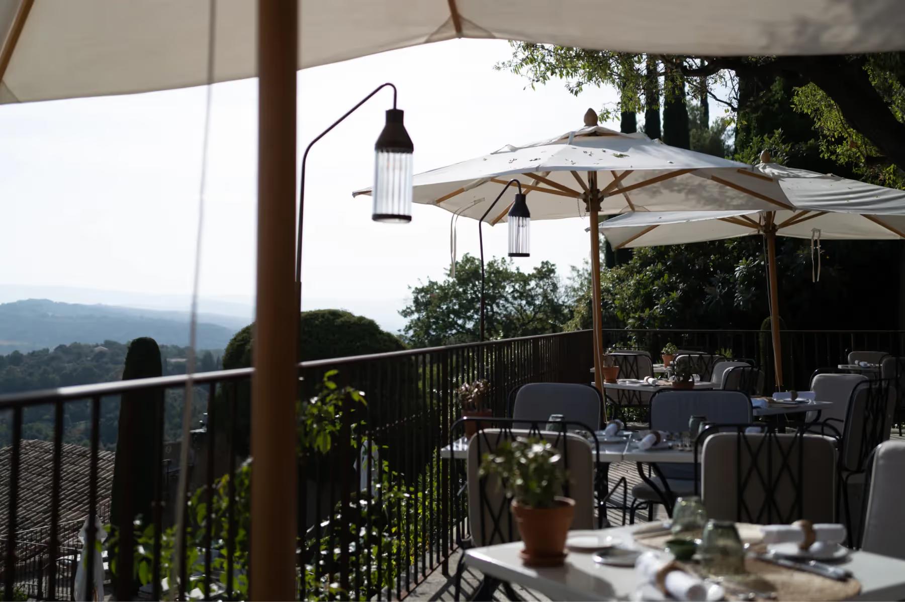 Hôtel Crillon le Brave: an outdoor terrace with table service, white umbrellas, and distant mountain views at a restaurant