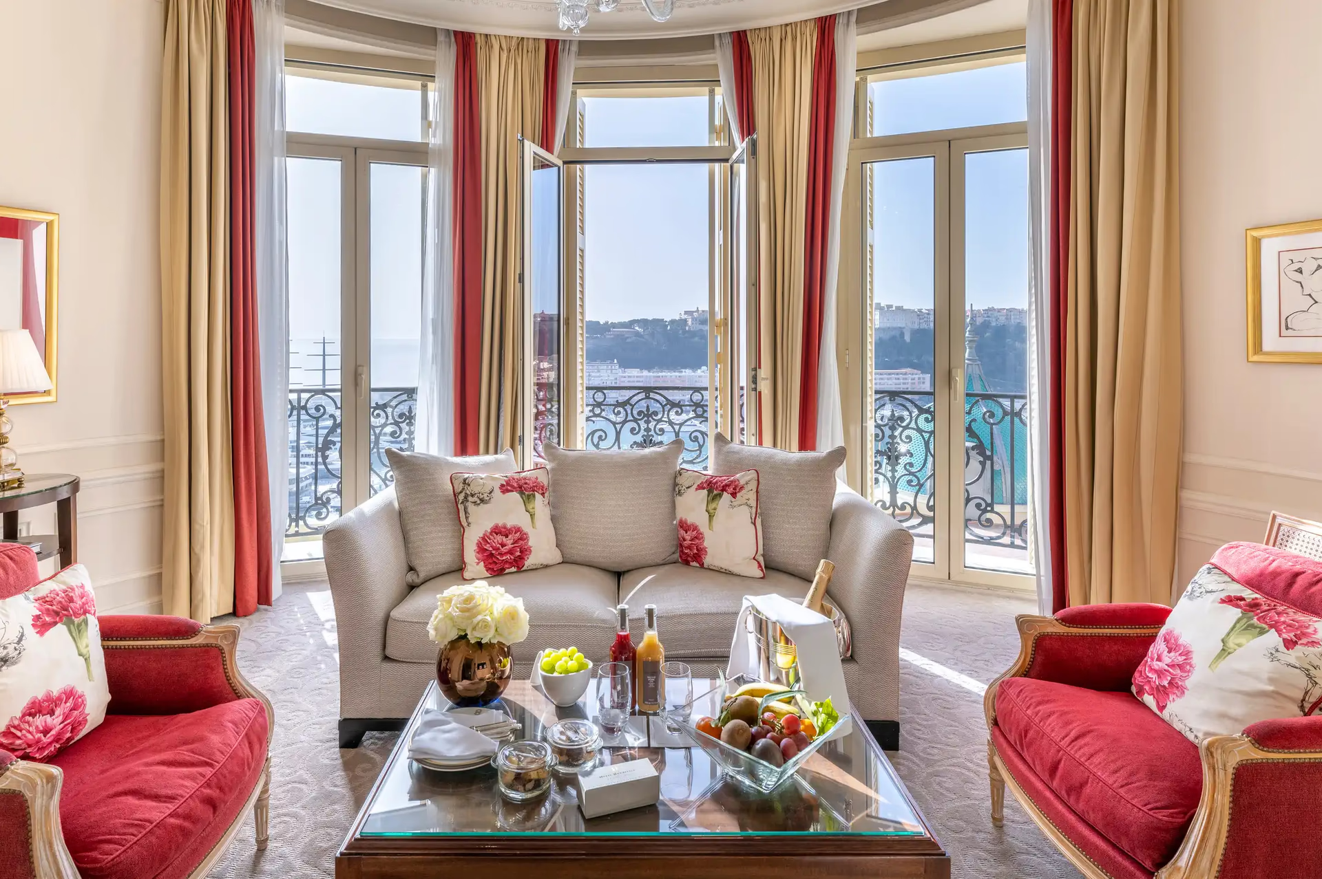 Hôtel Hermitage Monte-Carlo: living room with pink upholstered seating, arched windows and panoramic Mediterranean view