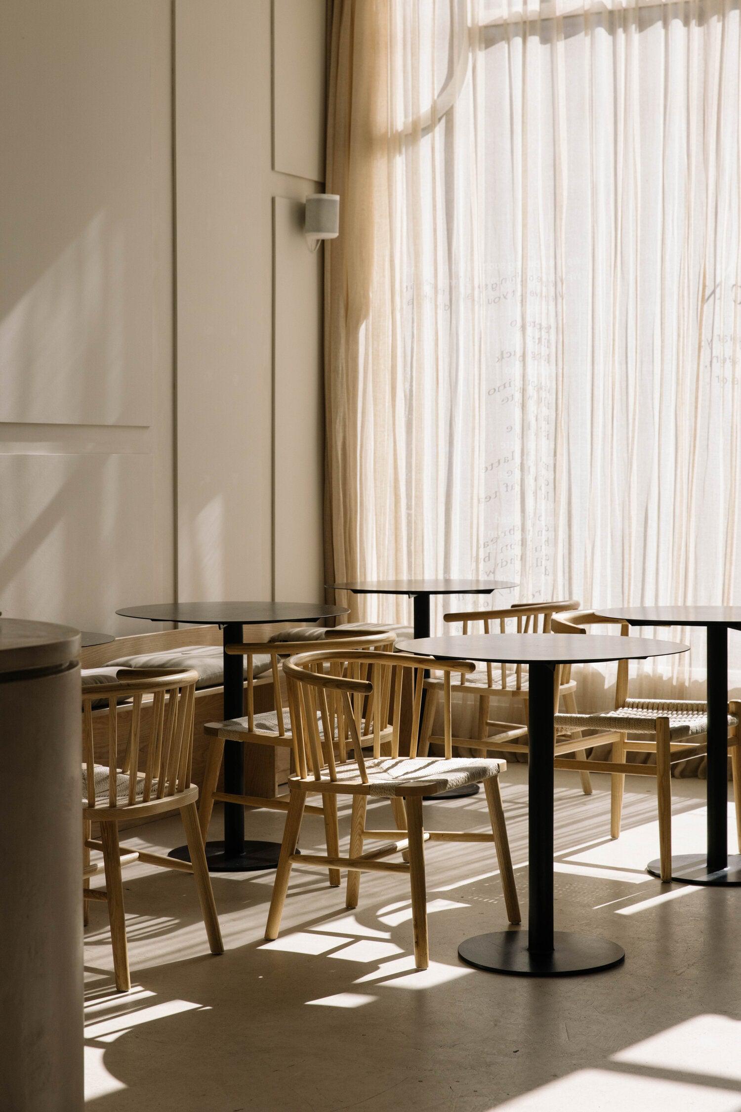 A sunlit seating corner at Uncommon, light through the printed curtain