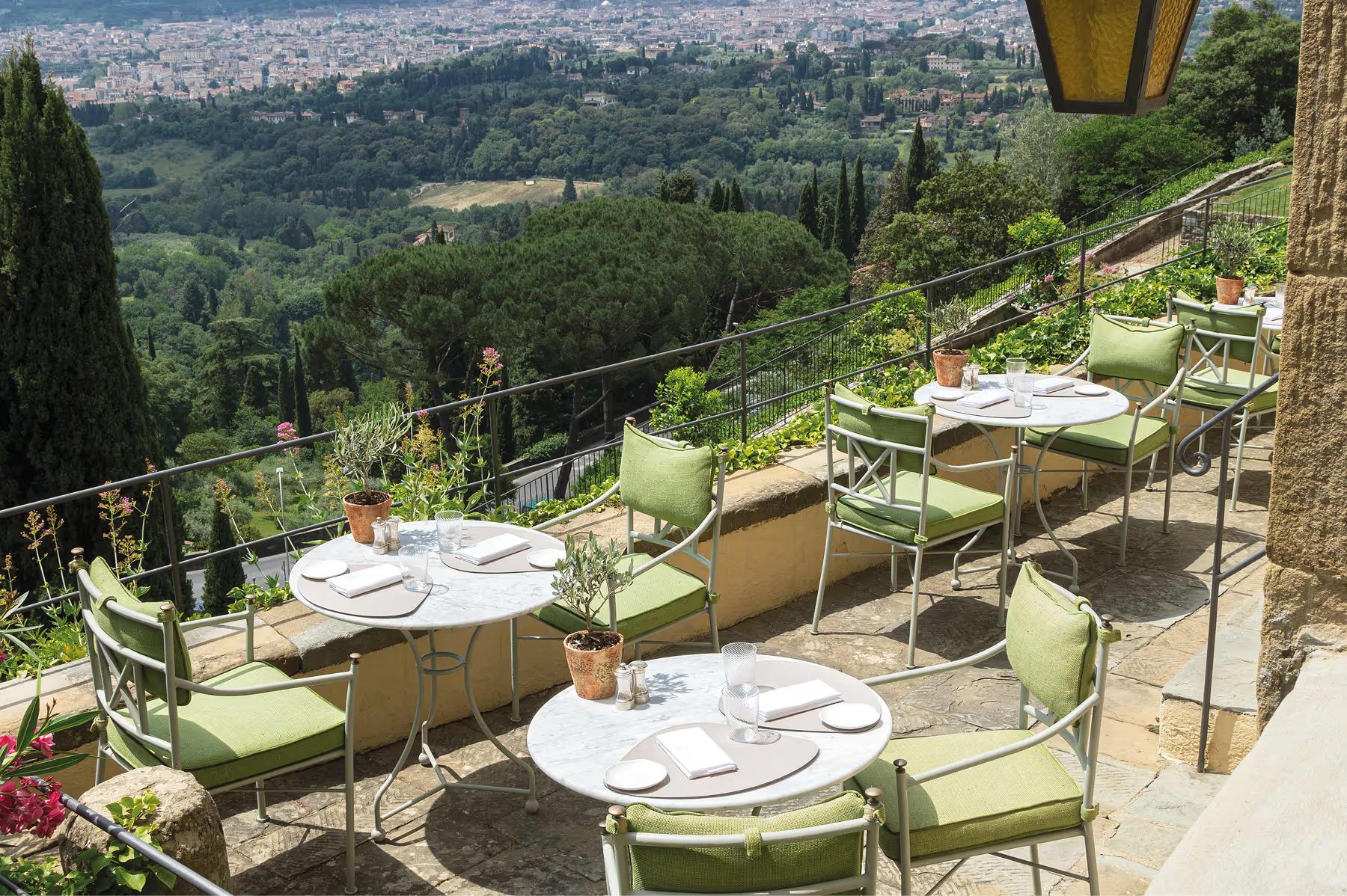 Villa San Michele: outdoor dining terraces with green chairs, white tablecloths, and sweeping views over the Tuscan landscape