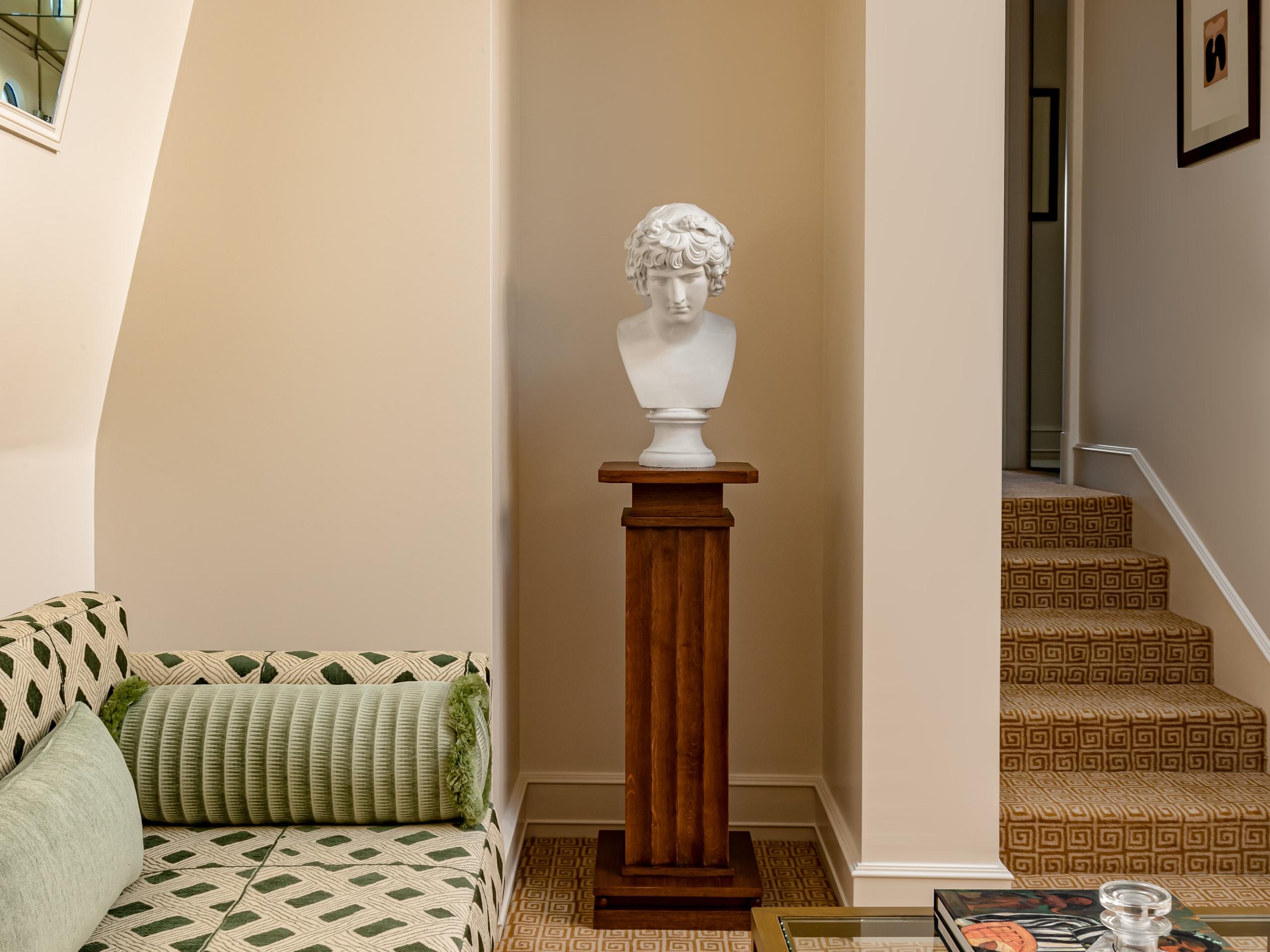 Saint James: hallway with sculptural marble bust on pedestal, cream walls, and classical archway entrance