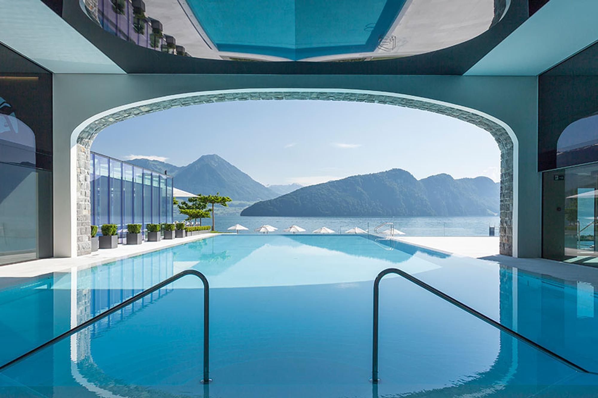 Indoor swimming pool with transparent ceiling and lake vista through large windows