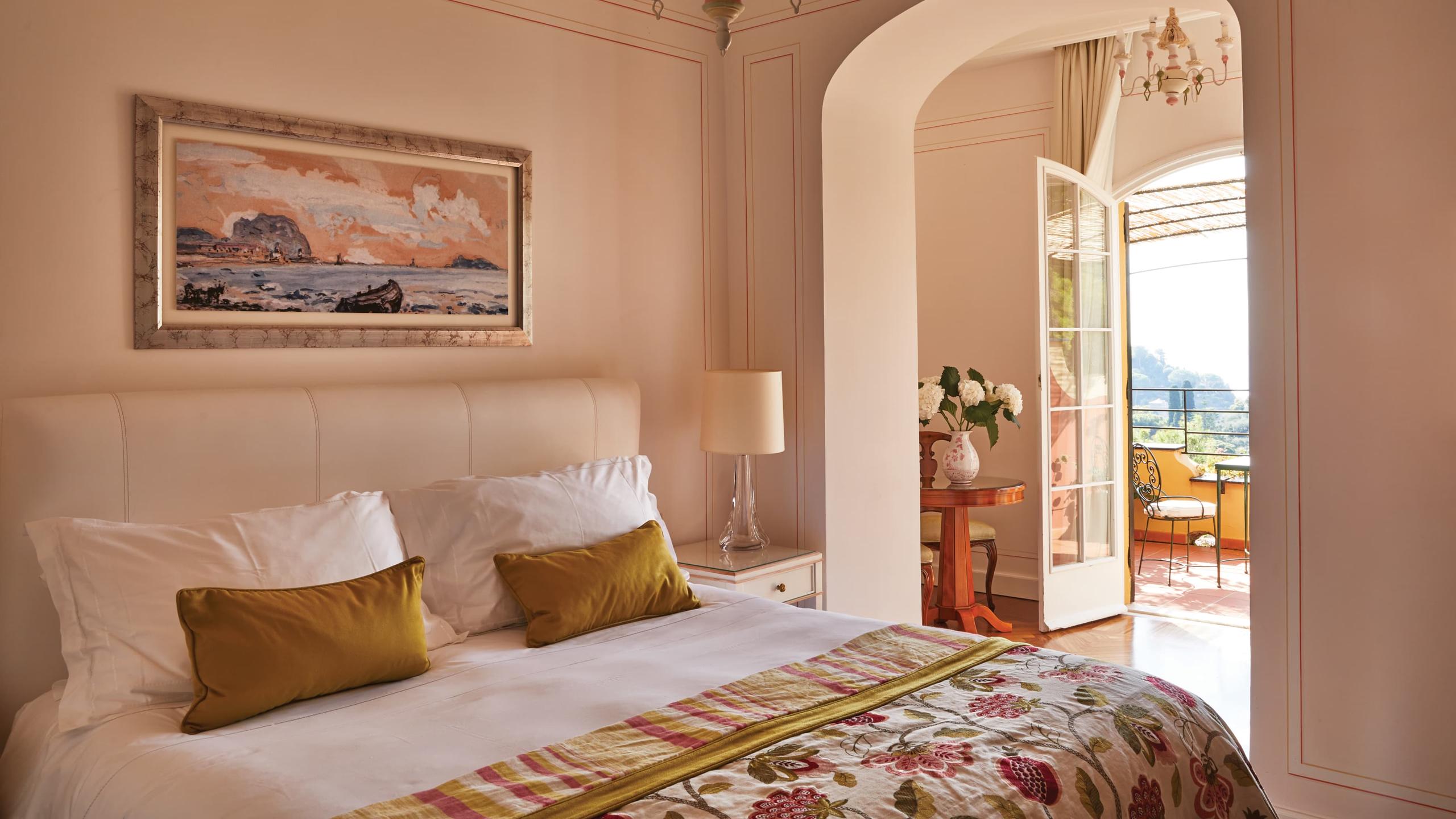 Splendido: a bedroom nook with upholstered chair, framed botanical art, and cream tufted headboard
