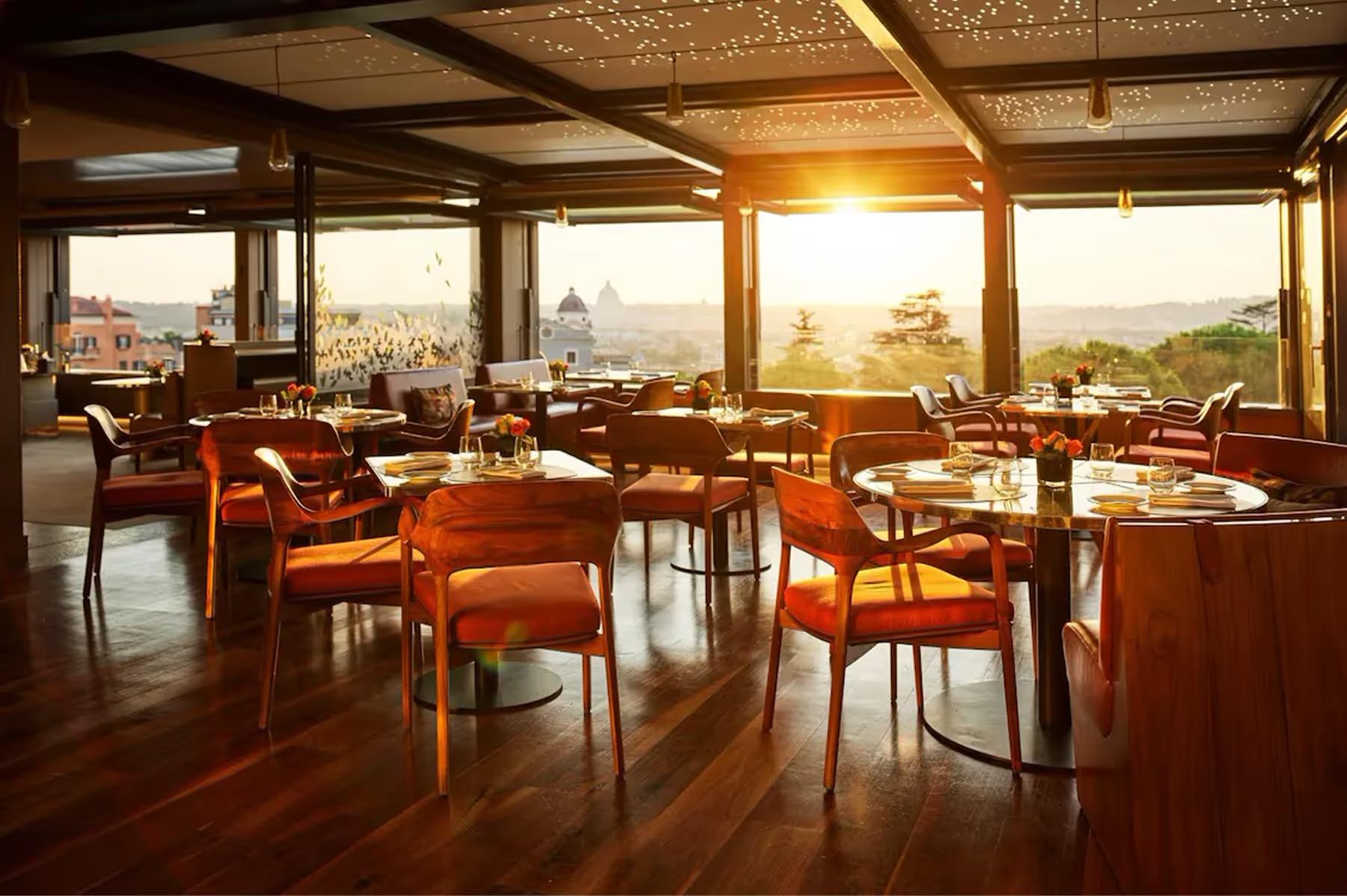 Hotel Eden: Il Giardino restaurant with wooden beams, orange leather chairs, and panoramic windows at sunset