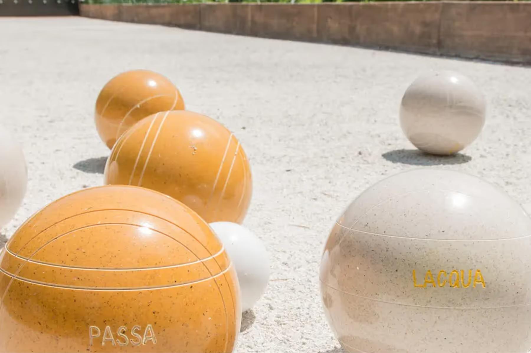 Passalacqua: bocce balls in tan and white on a stone surface, branded with property name