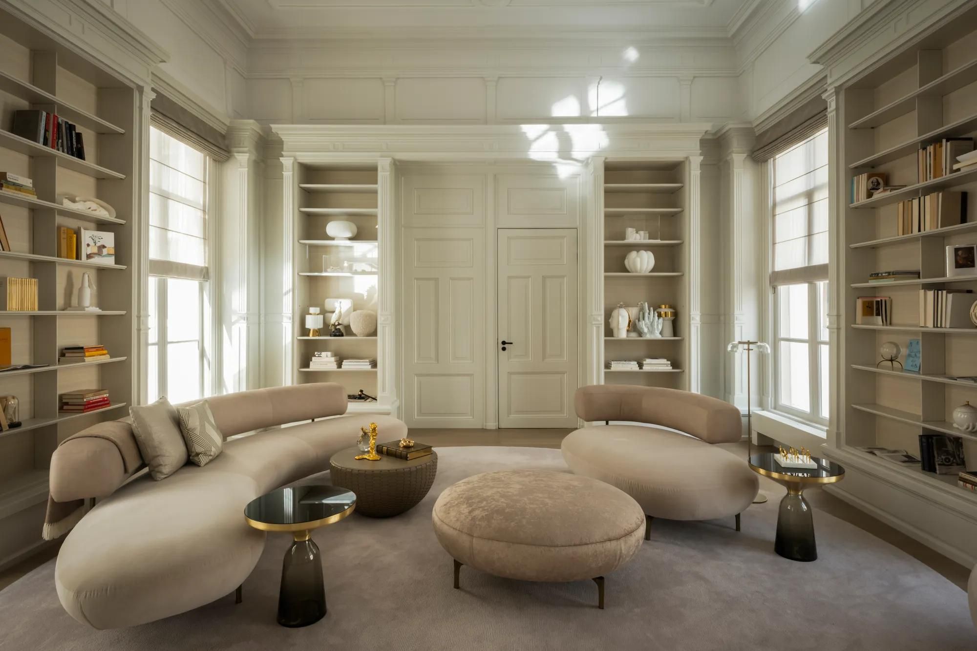 Rosewood Amsterdam: the Library House living room with floor-to-ceiling bookshelves and curved sofas