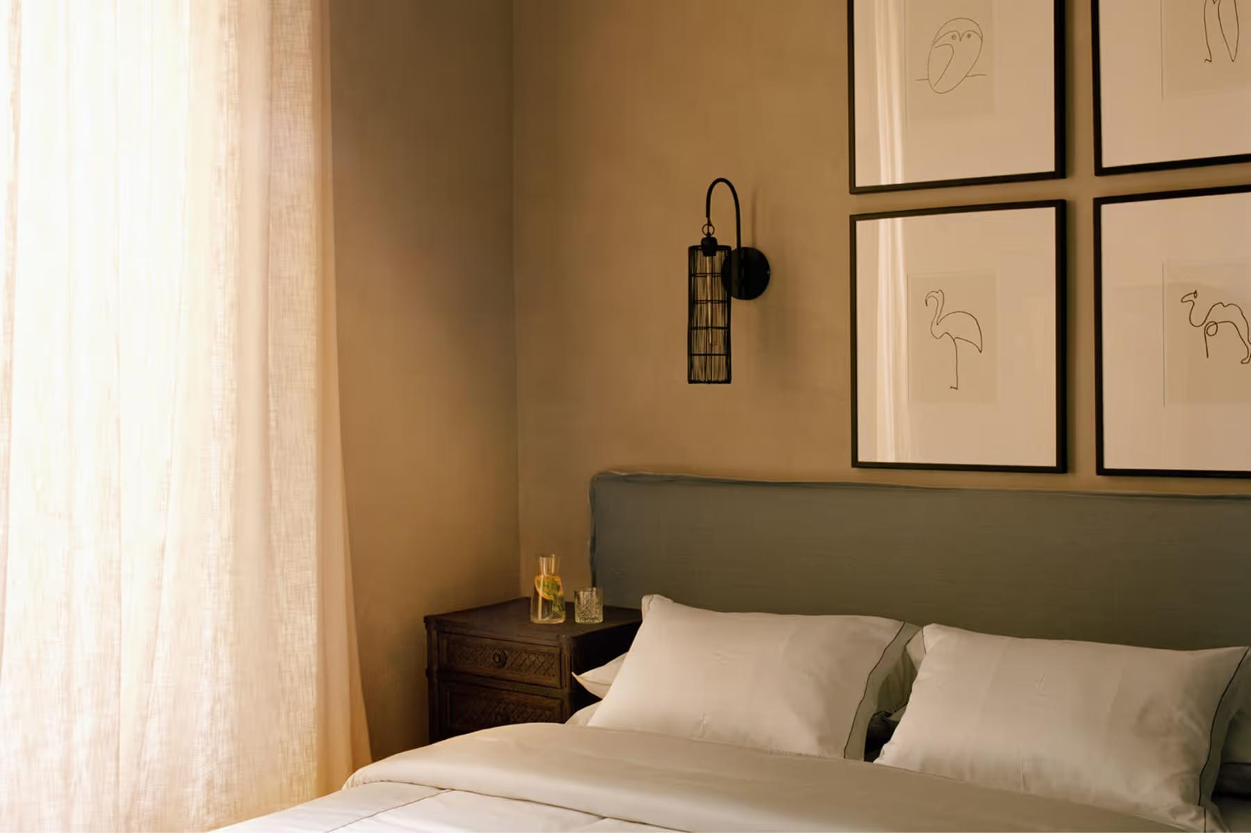 Le Mas de Chabran: bedroom with olive-green headboard, framed wall art, and warm incandescent lighting