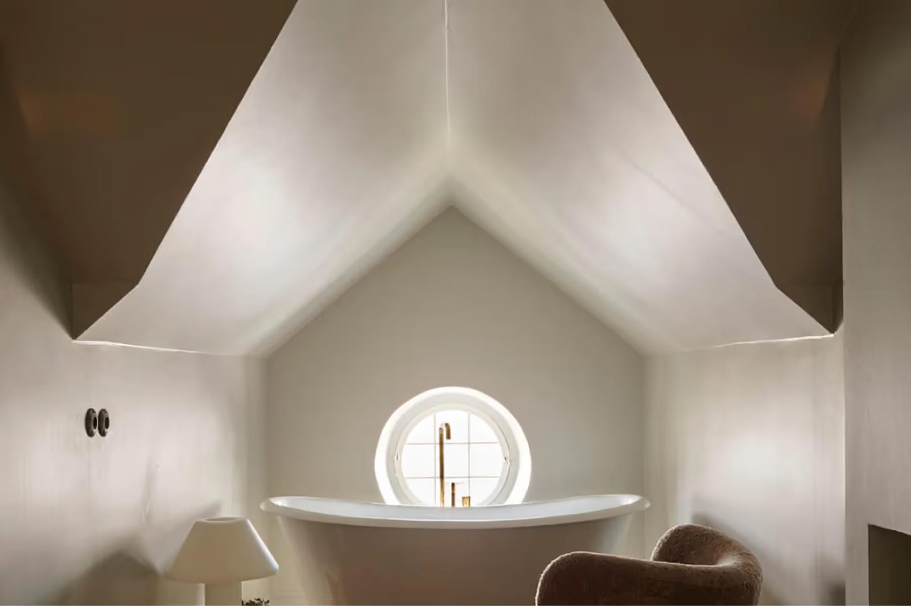 An angular white ceiling with a circular skylight opening to blue sky