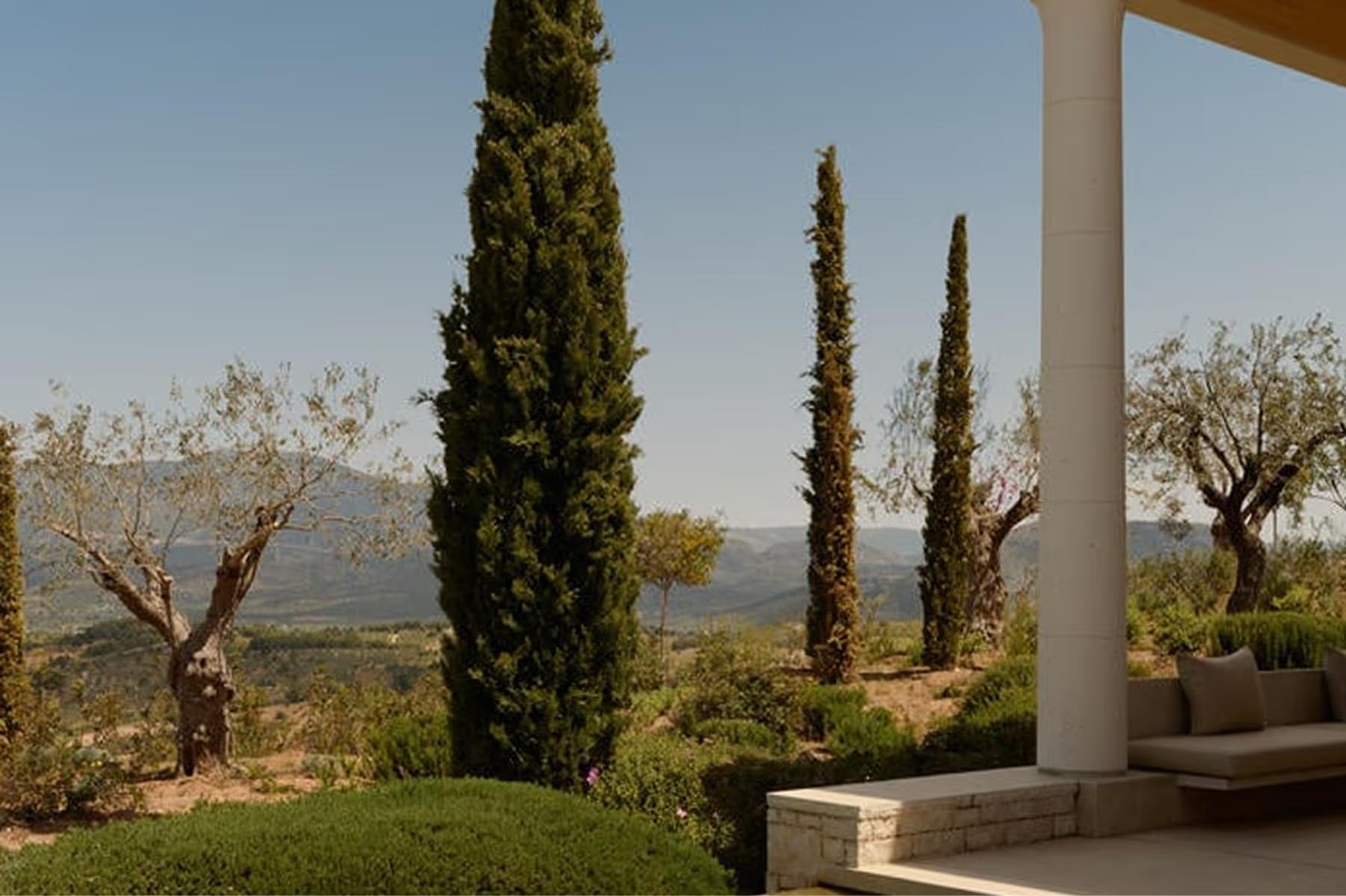 Amanzoe: terrace overlook with cypress trees and columned pergola framing the landscape