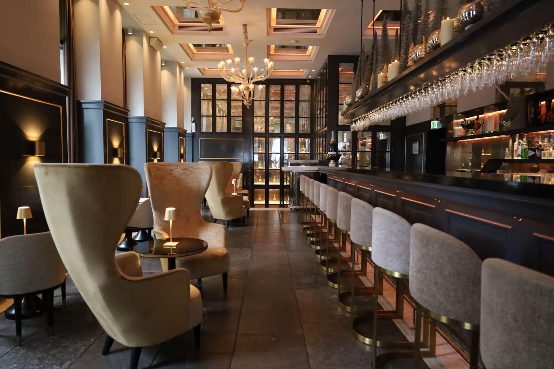 Hotel d’Angleterre: bar counter with tall upholstered chairs and interior display shelving
