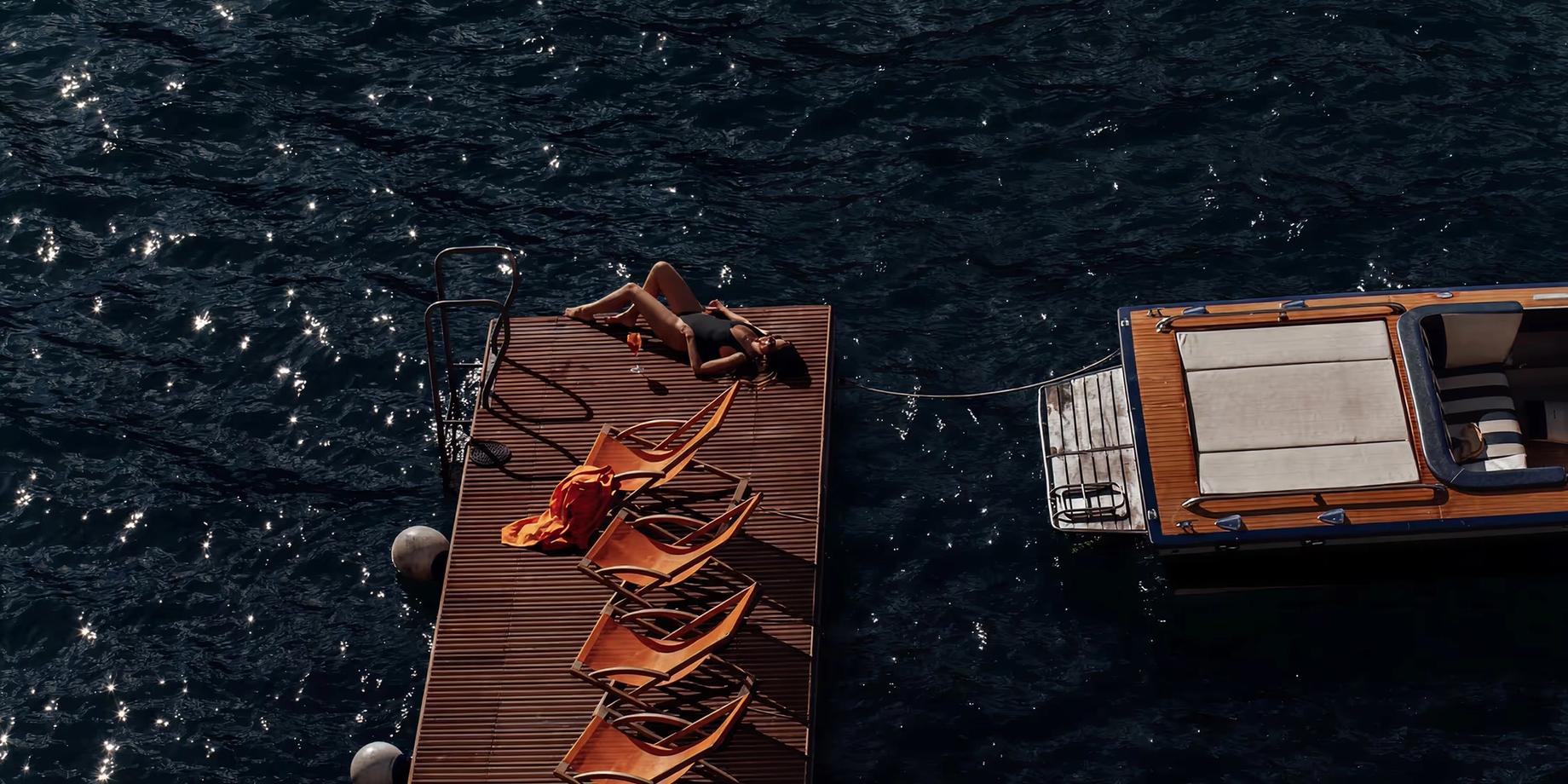 Wooden sunloungers with golden rope detail on a dark water surface