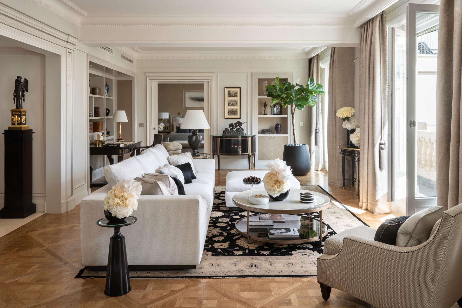 Four Seasons Hotel George V: a living area with white armchairs, a black accent cabinet, and sunny windows