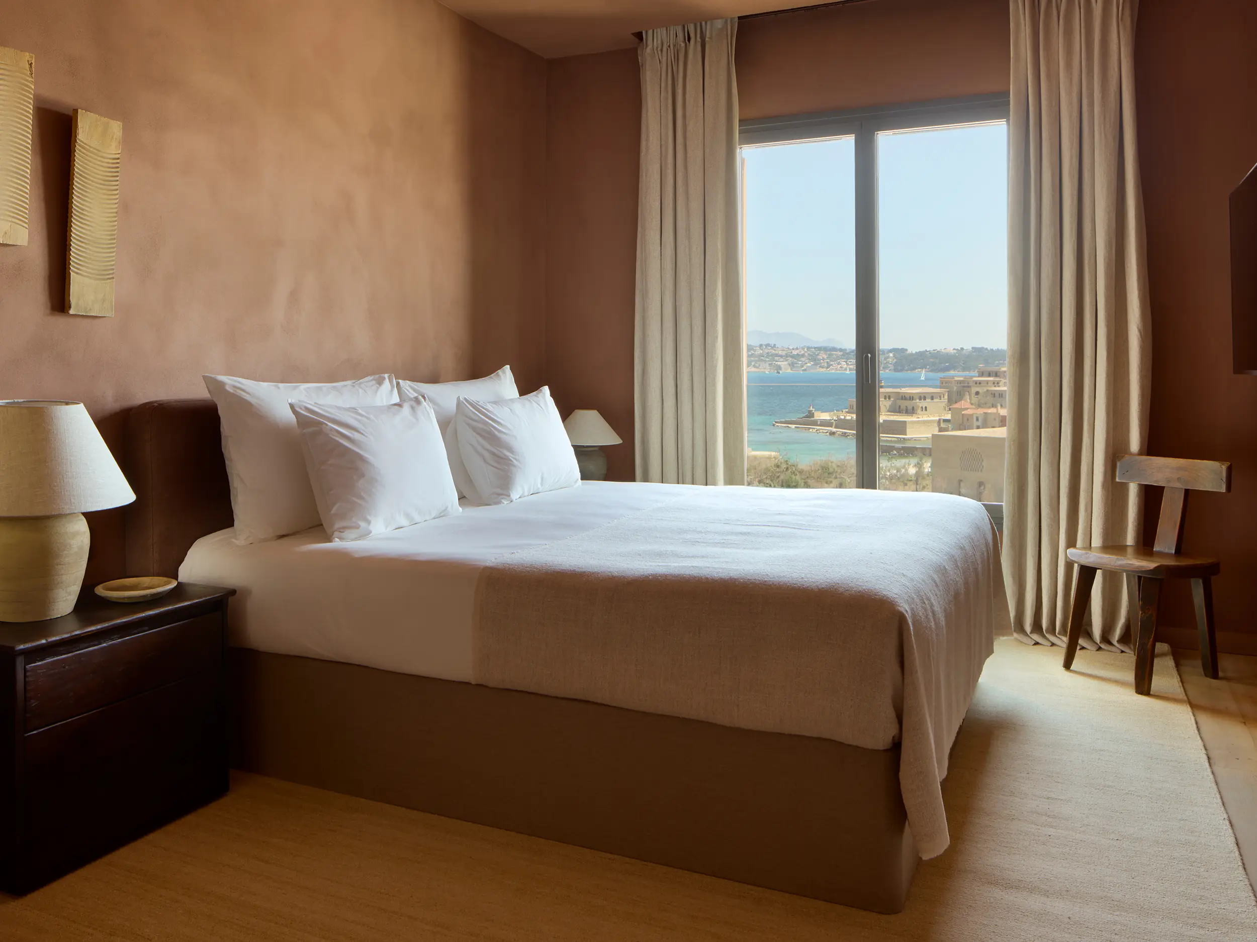 Zannier Île de Bendor: pillows are piled high on a bed facing arched windows over the sea and stone ramparts