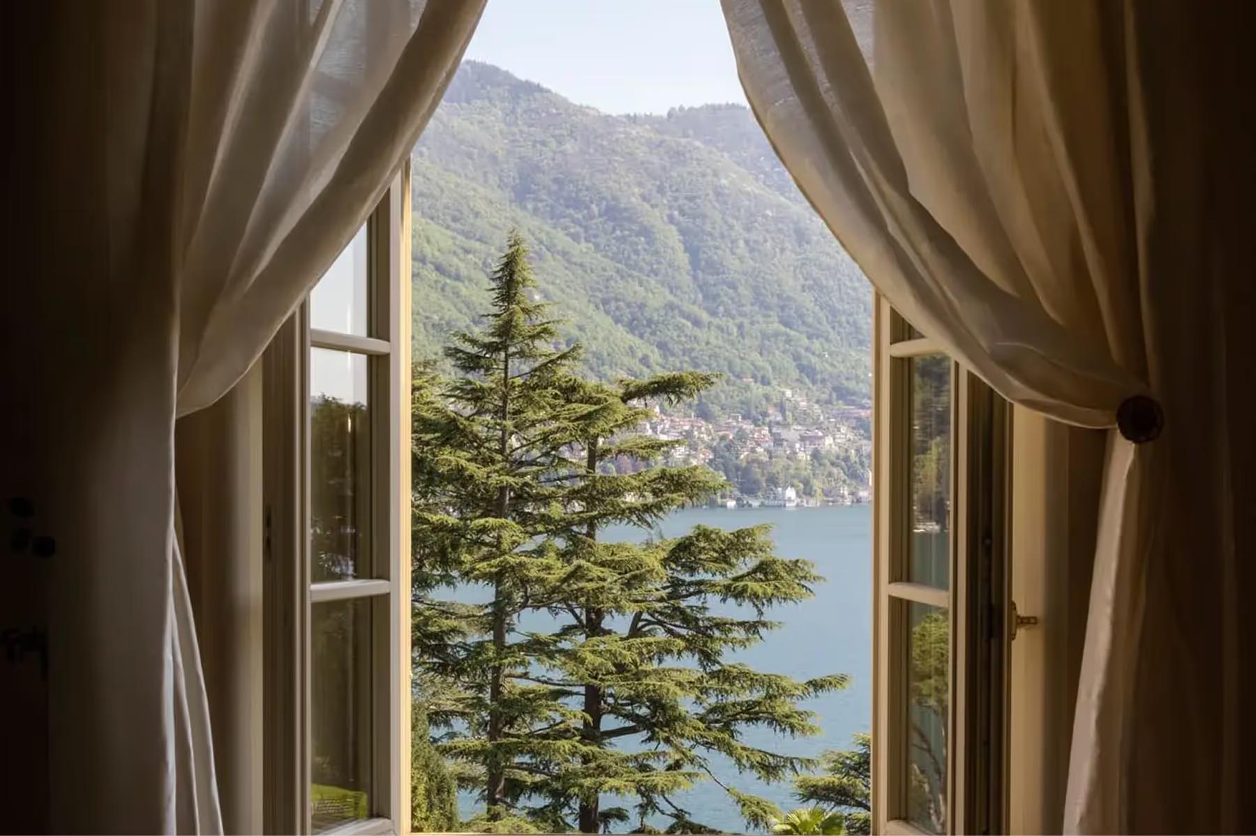 Passalacqua: open French doors framing a lake and cypress trees beyond sheer curtains