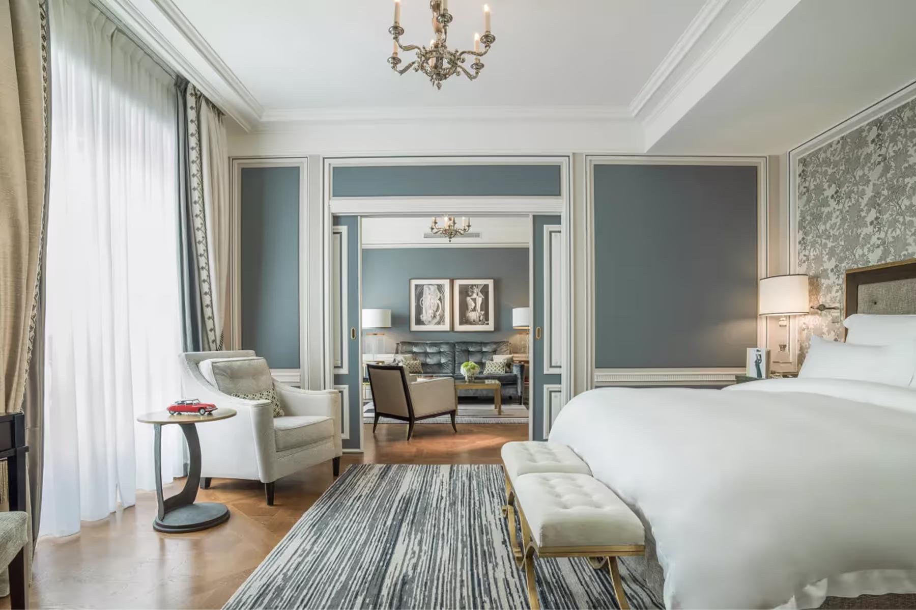 Hôtel de Crillon: generous bedroom with blue accents, crown ceiling, and multiple seating areas